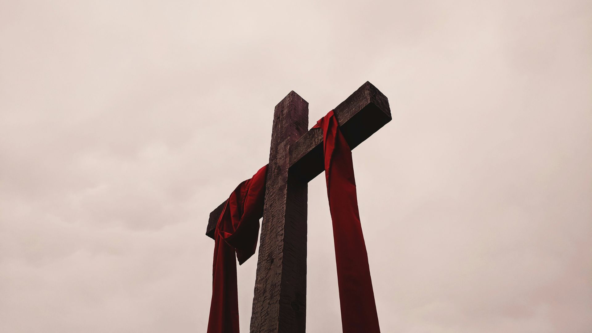 Large cross standing against the sky with a red garment draped over it
