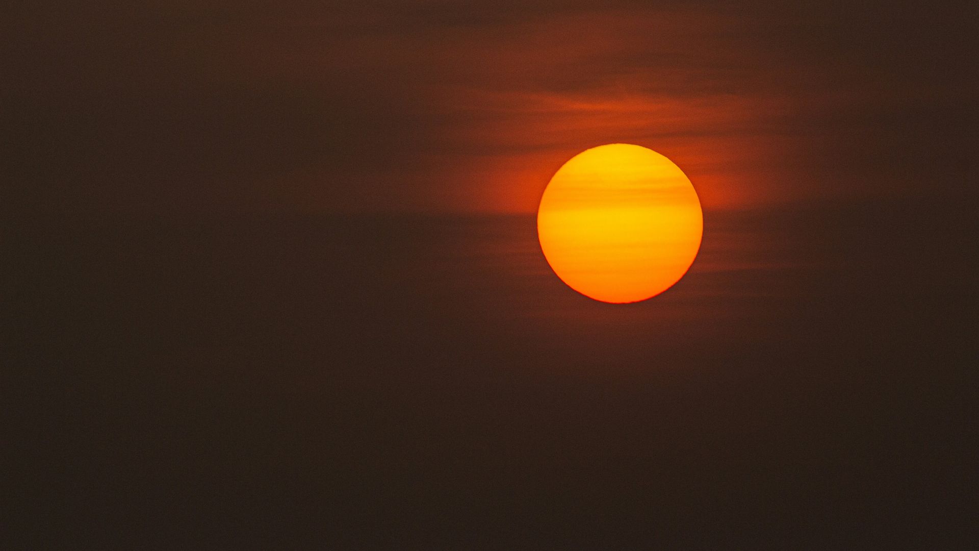Low light photograph of the sun partially obscured in a dark sky.