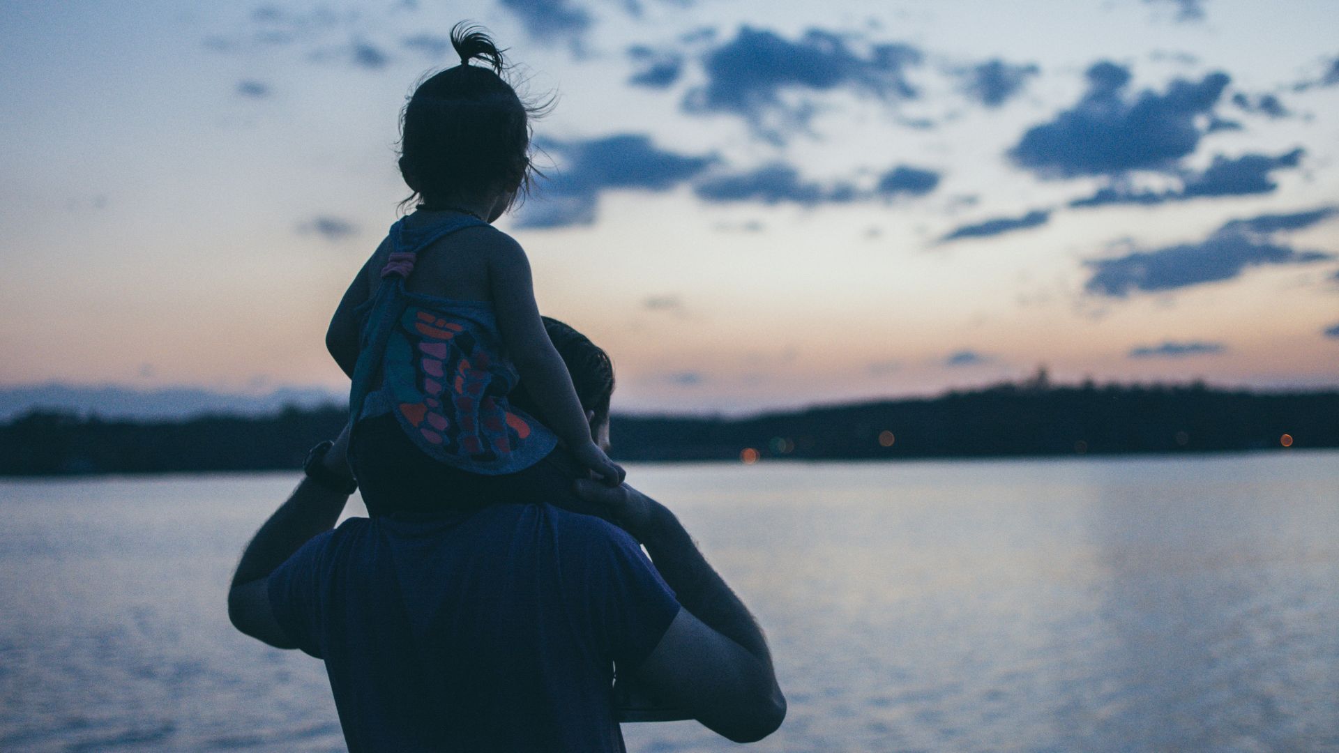 Man carrying a young girl outdoors with warm lighting