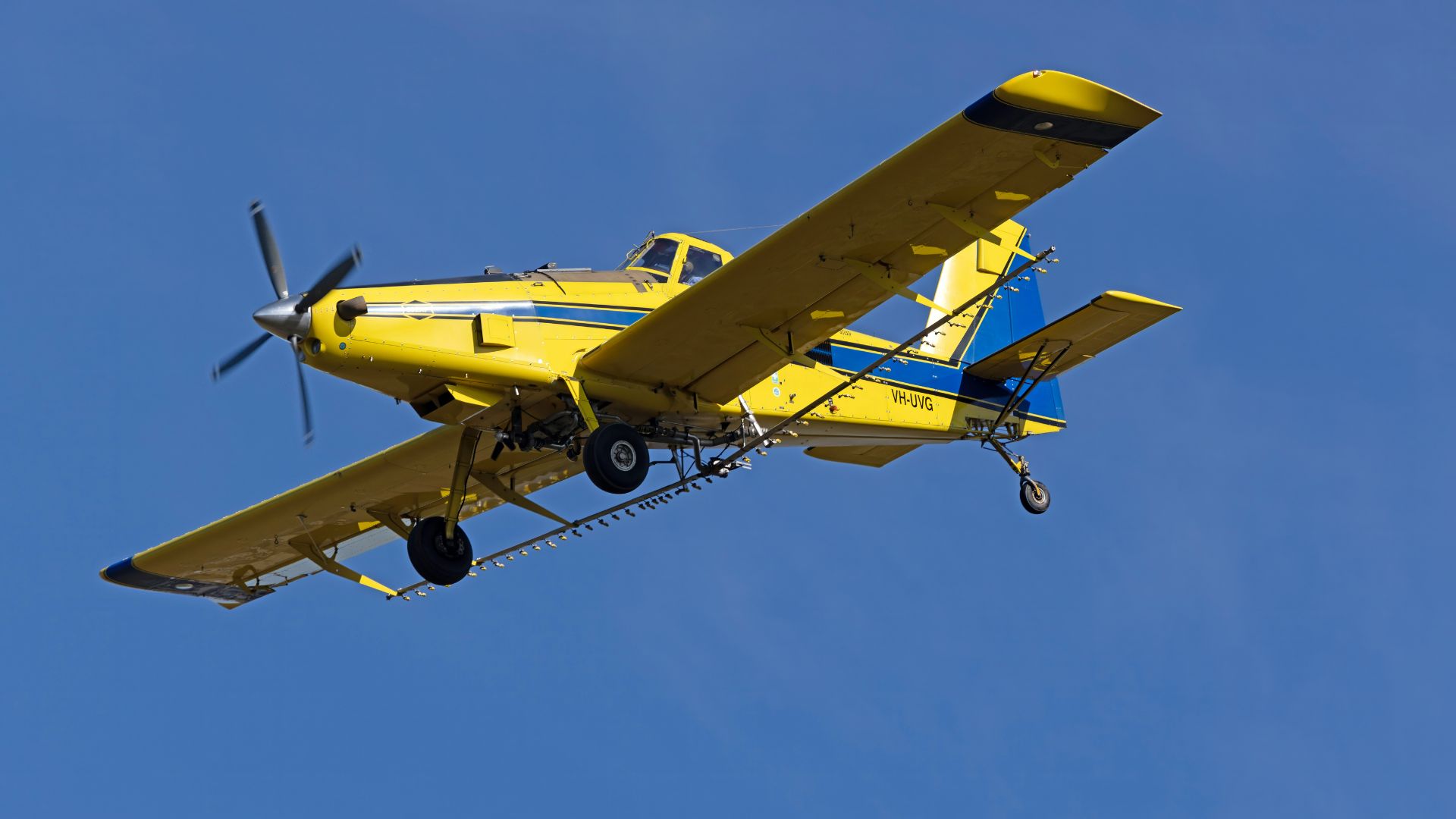 Small yellow airplane flying through clear blue sky