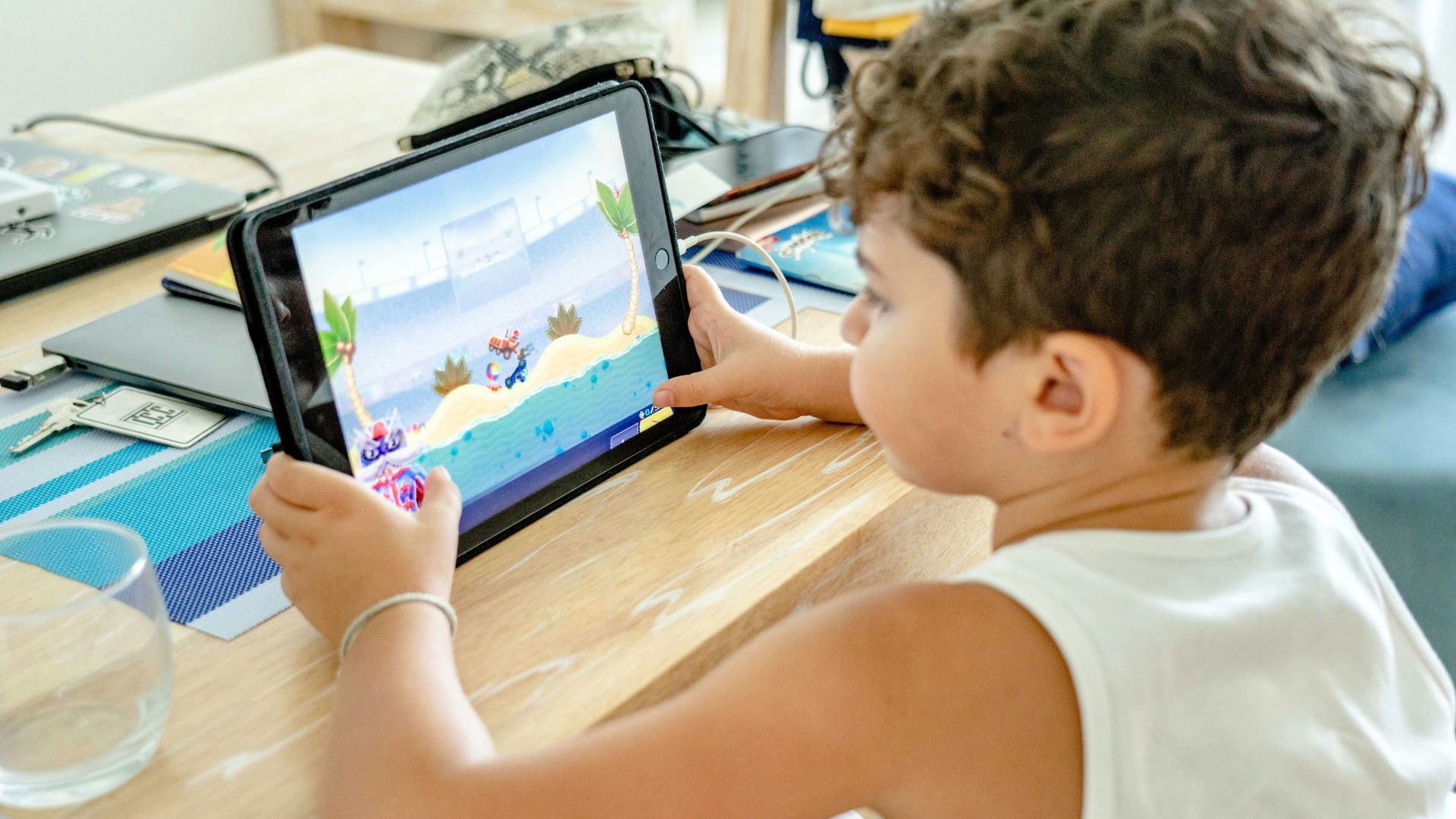 Young boy wearing a white tank top playing on a tablet