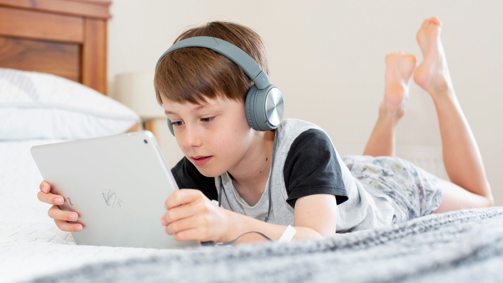Young boy using an iPad on a bed