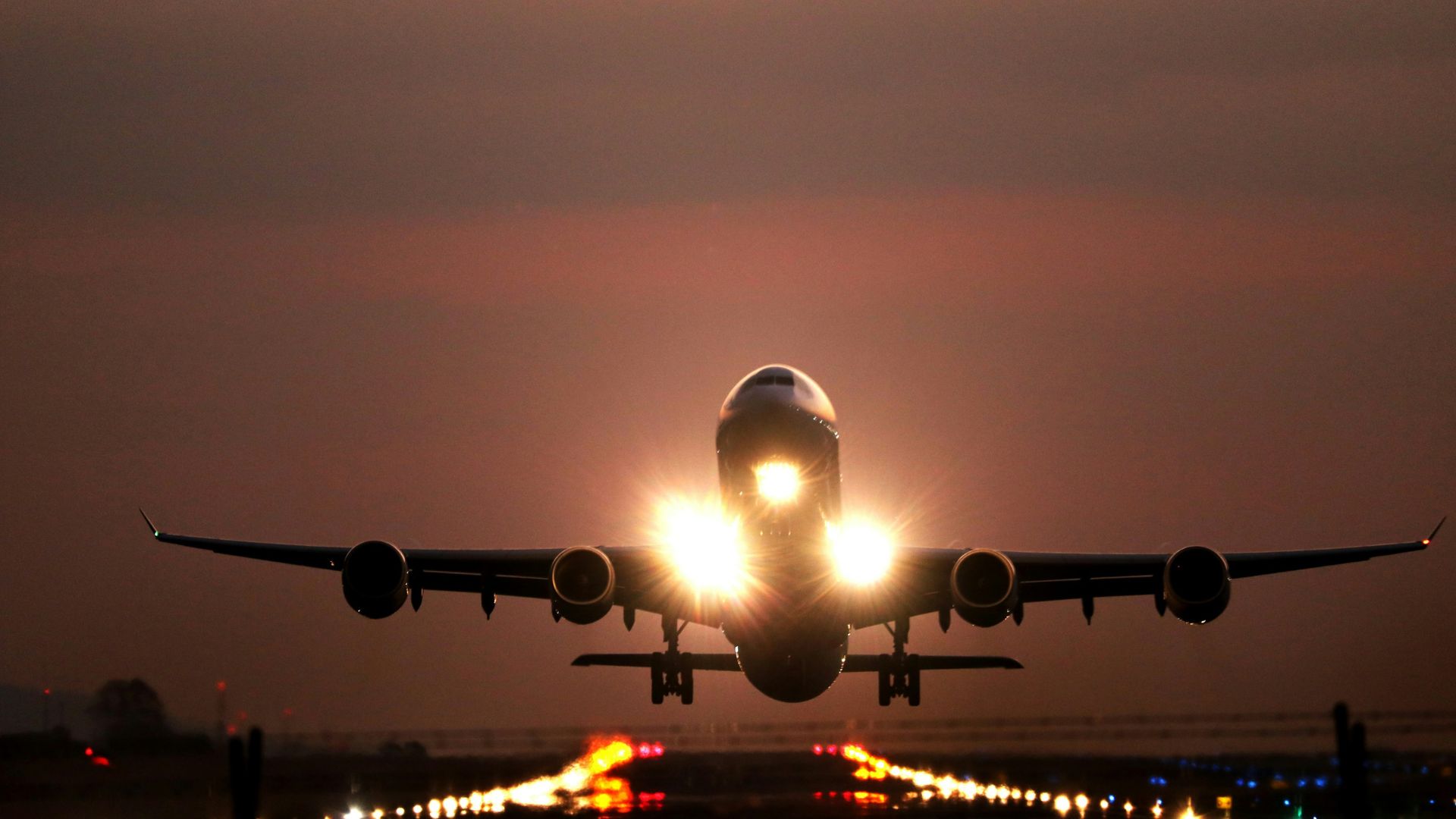 Passenger plane descending toward a runway with landing gear extended.