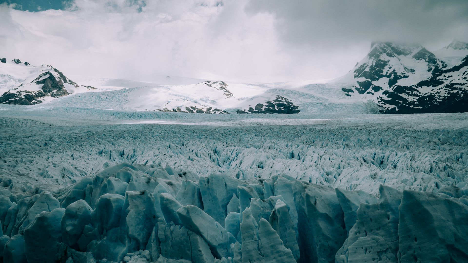 Snow covered Arctic mountains under cloudy daylight.