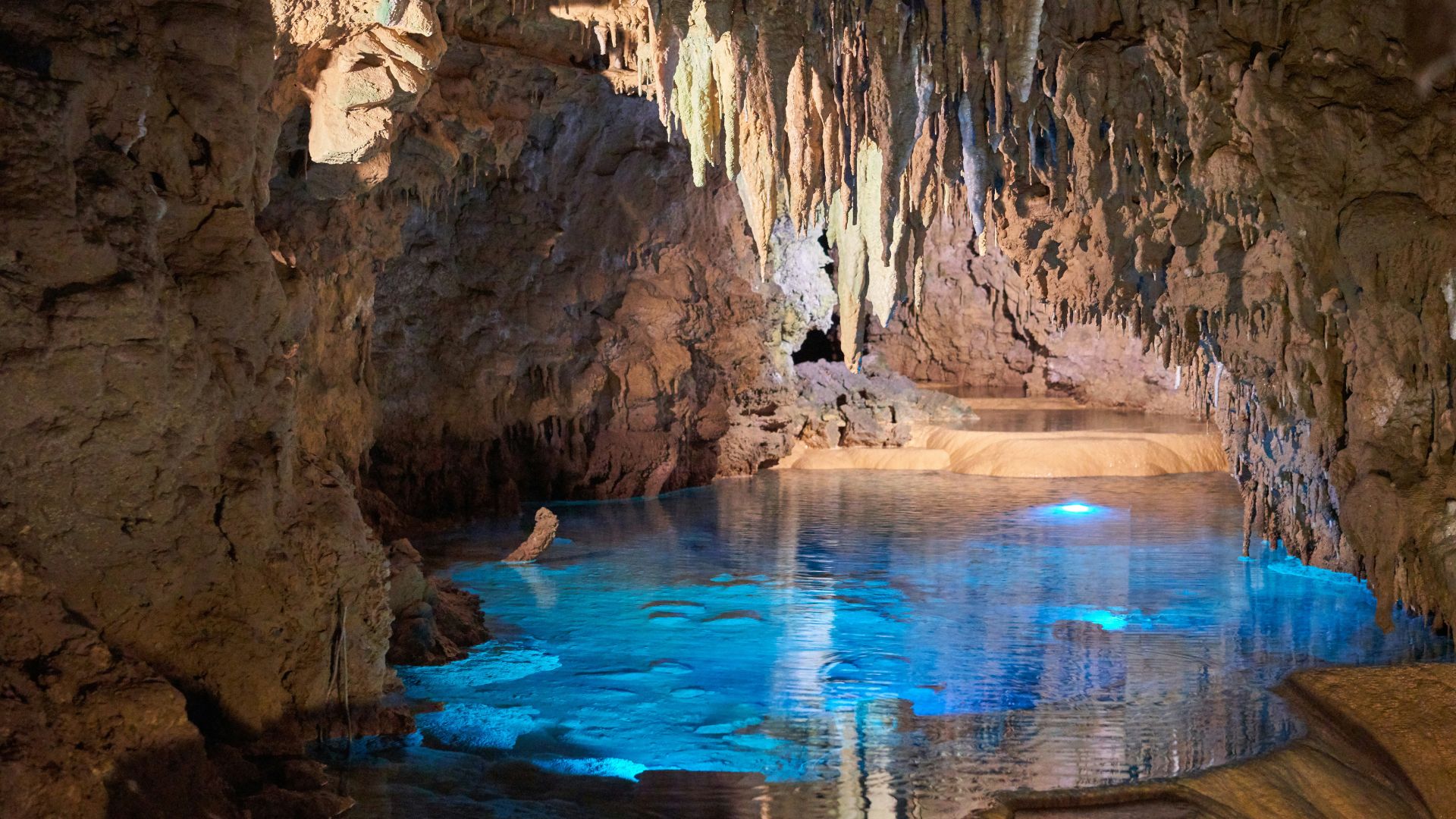 Sunlit sea cave with calm turquoise water and rocky rock walls