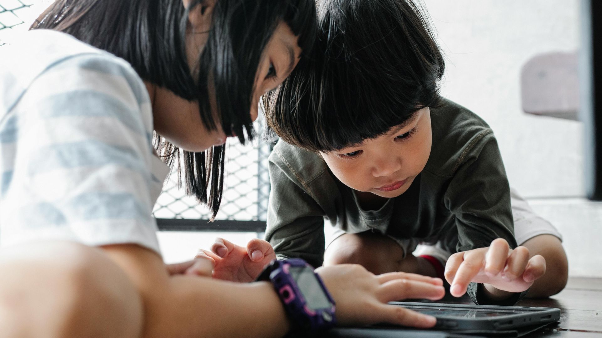 Group of kids sitting together and playing on tablets