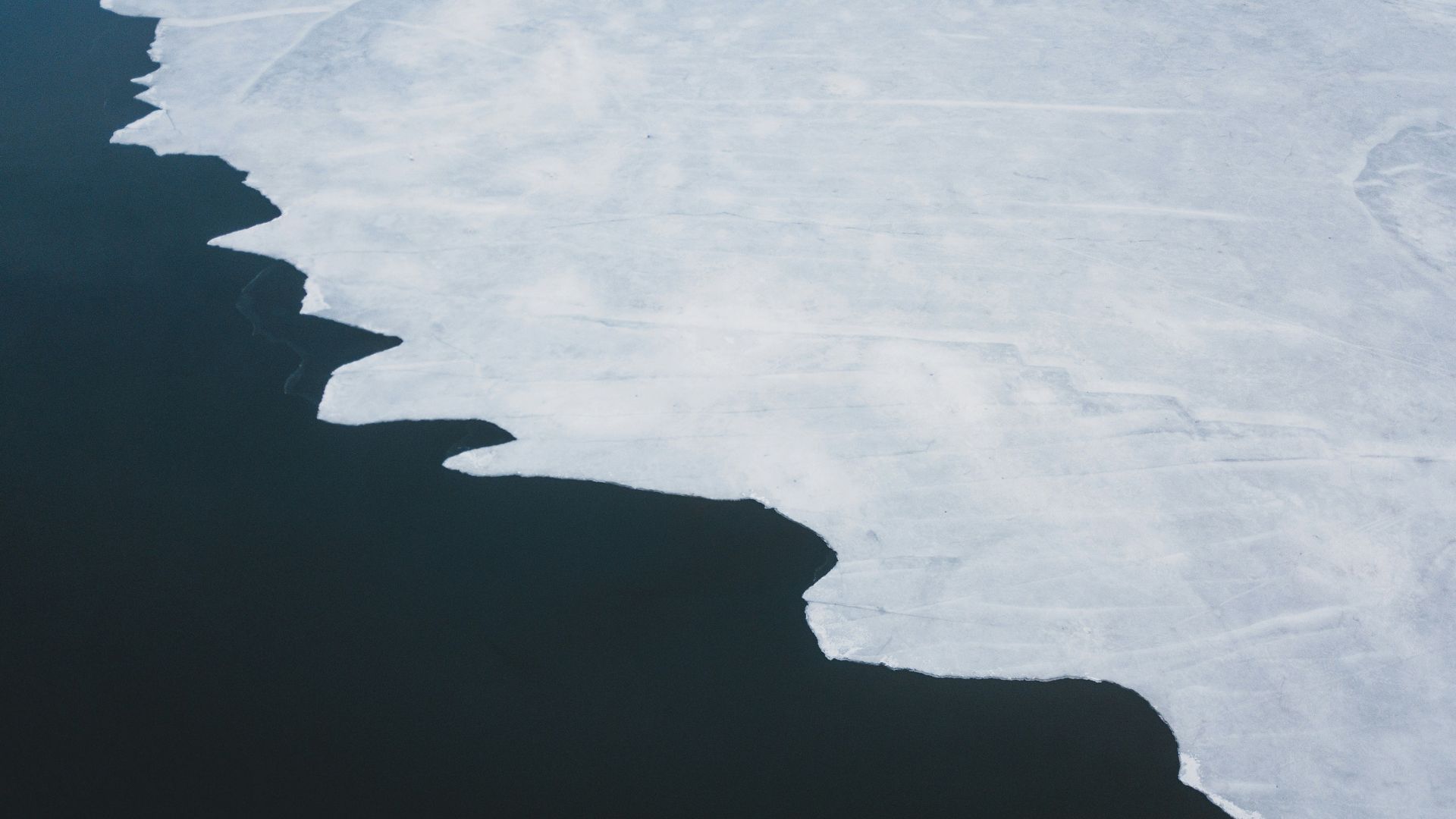 Snow-covered mountain landscape viewed from above with ridges and ice formations