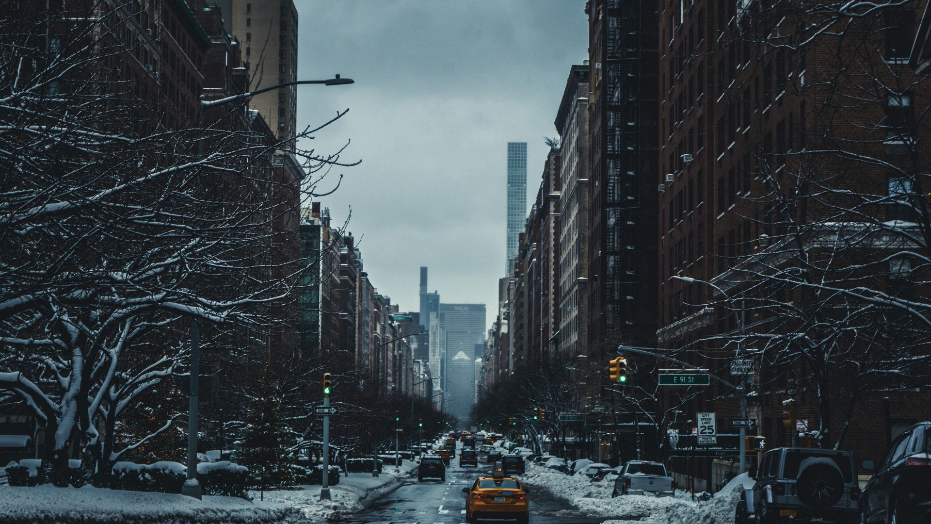 Cars driving on a city road between tall buildings