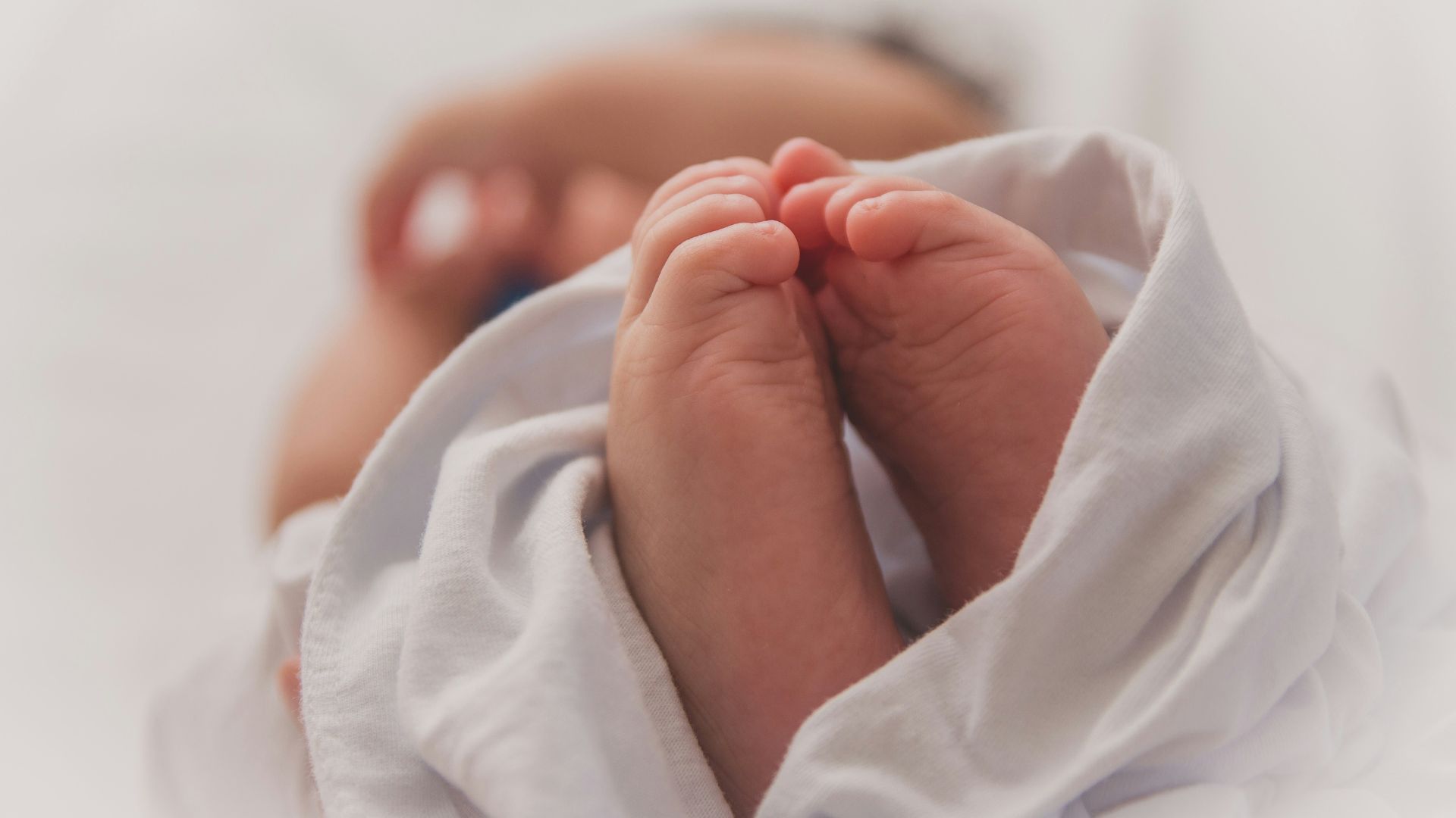 Baby covered with a white blanket while resting