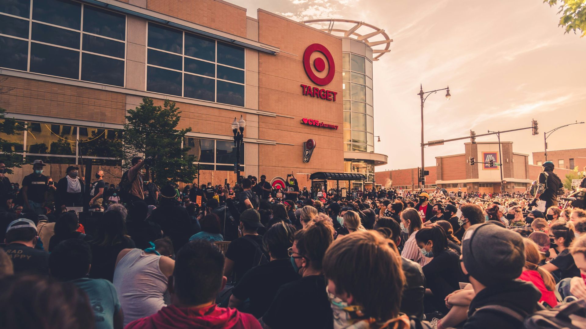 Crowd of people gathered in front of a large building during a daytime protest.
