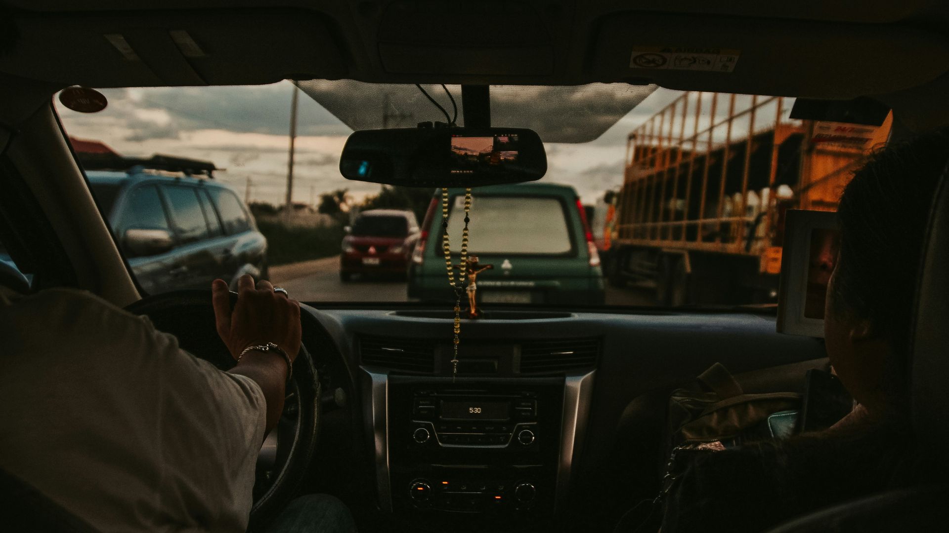Driver steering a car down a quiet street in daylight