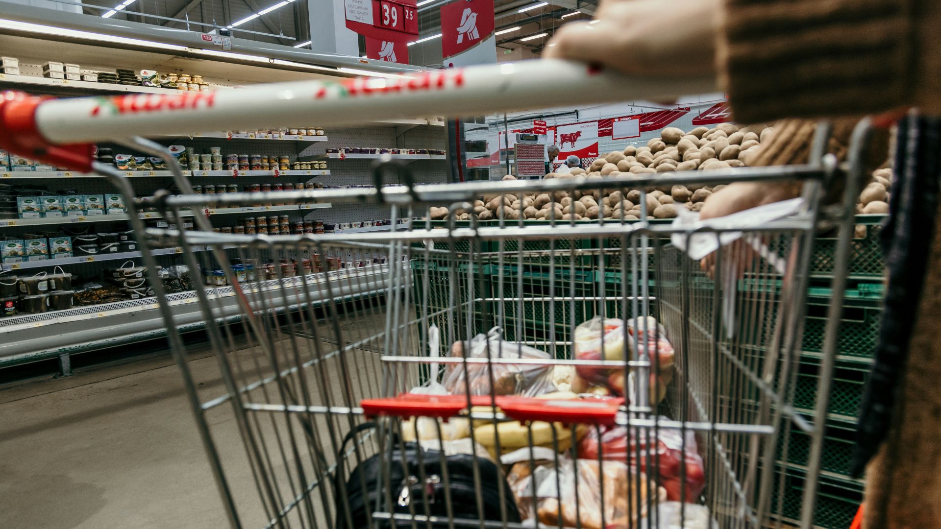 White and red metal birdcage hanging against a neutral background.