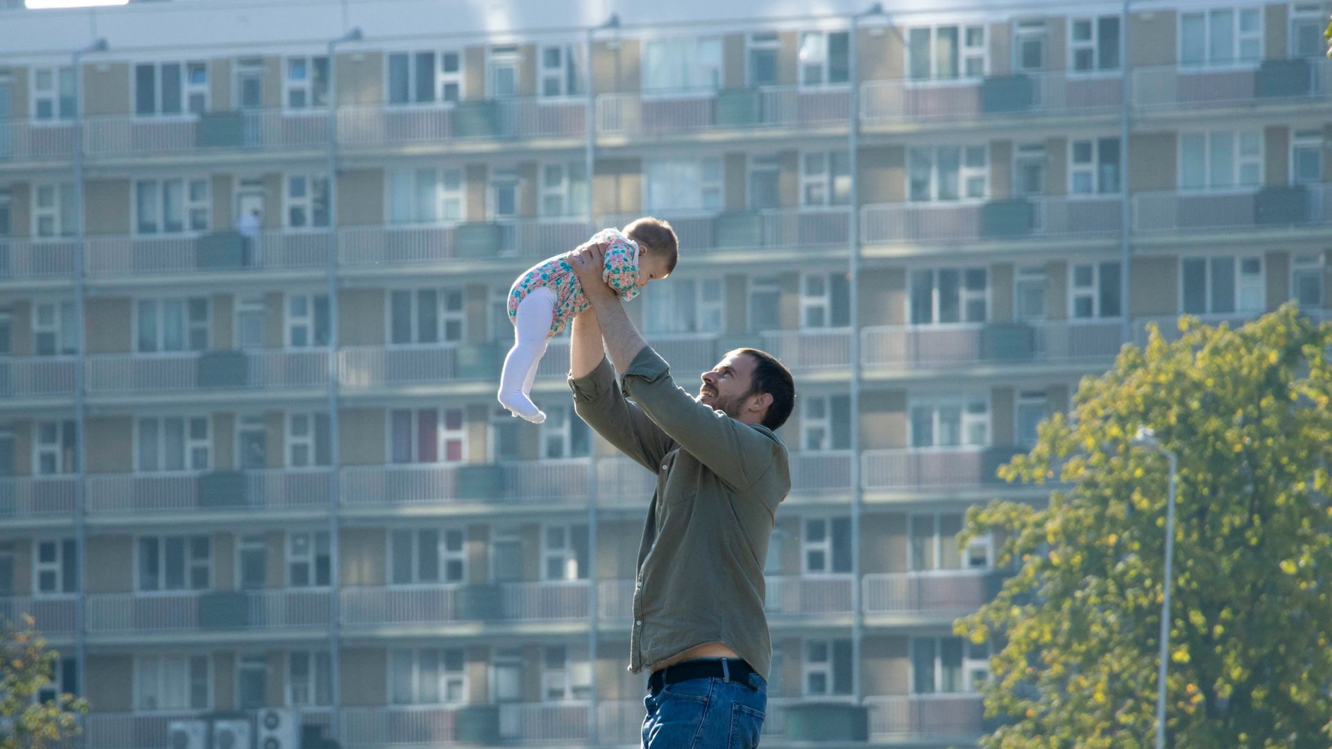 Man lifting a baby into the air while smiling