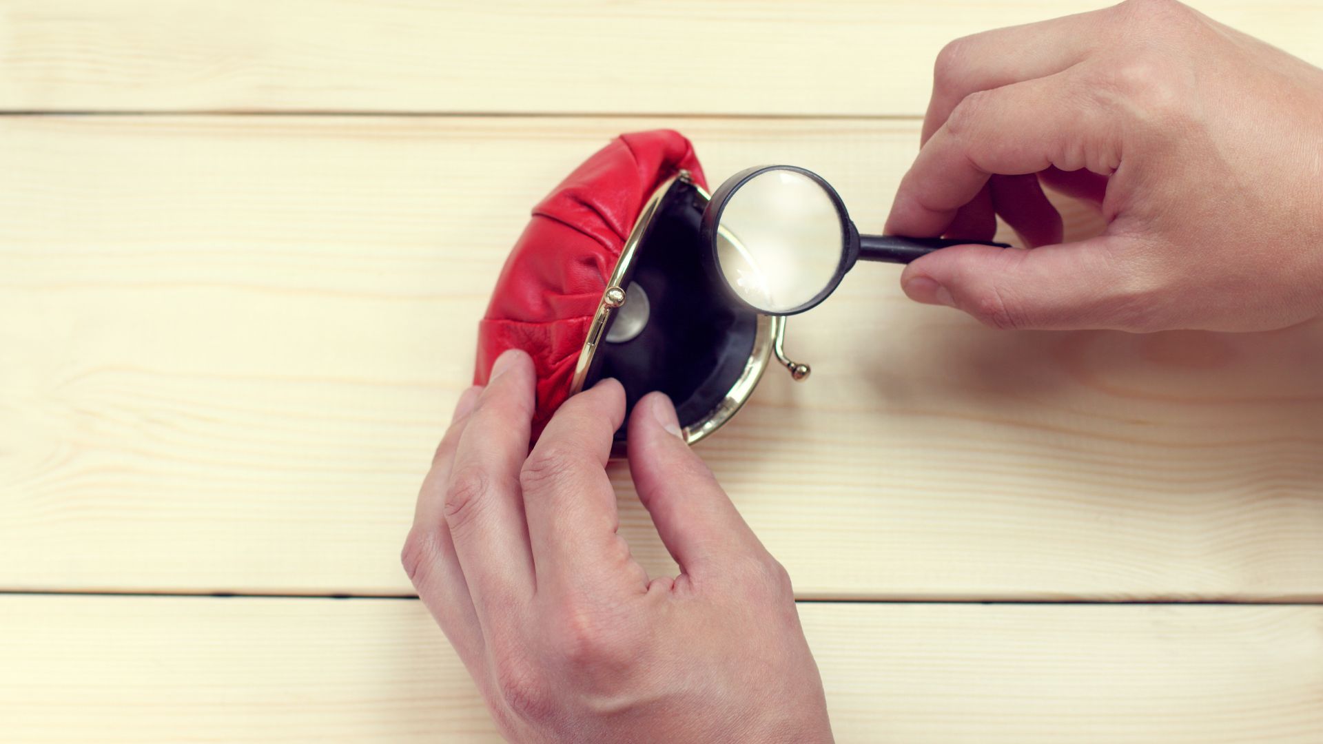 A person looking into a change purse with a magnifying glass