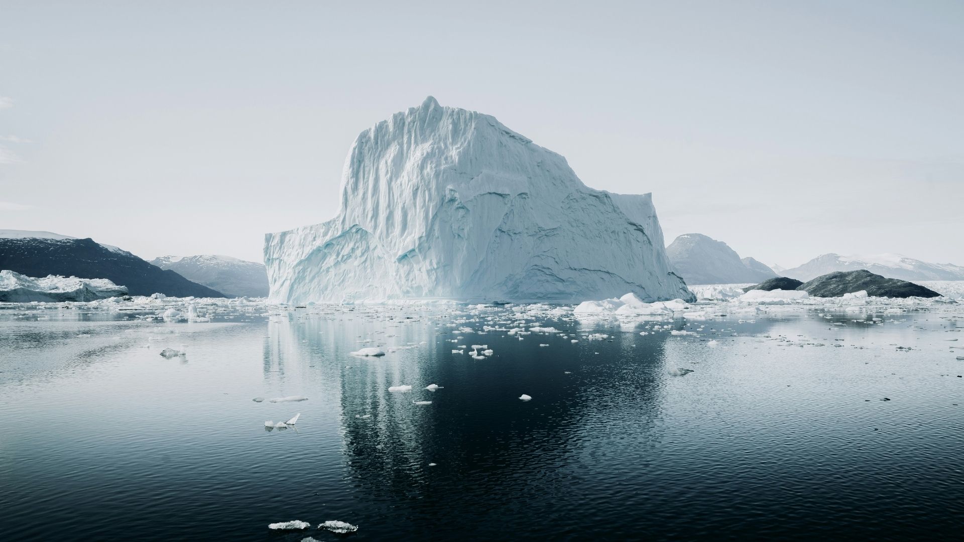 Iceberg resting beside a river with exposed rock and melting ice
