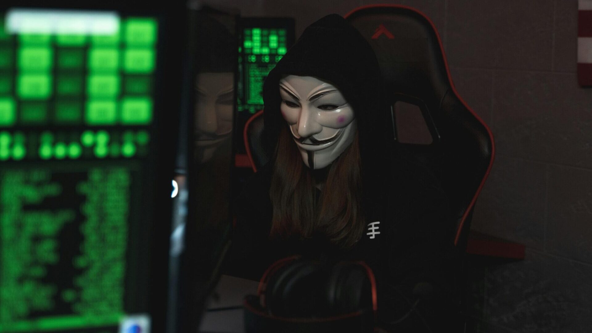 Person wearing a mask while sitting at a desk and using a computer, focused on the screen.