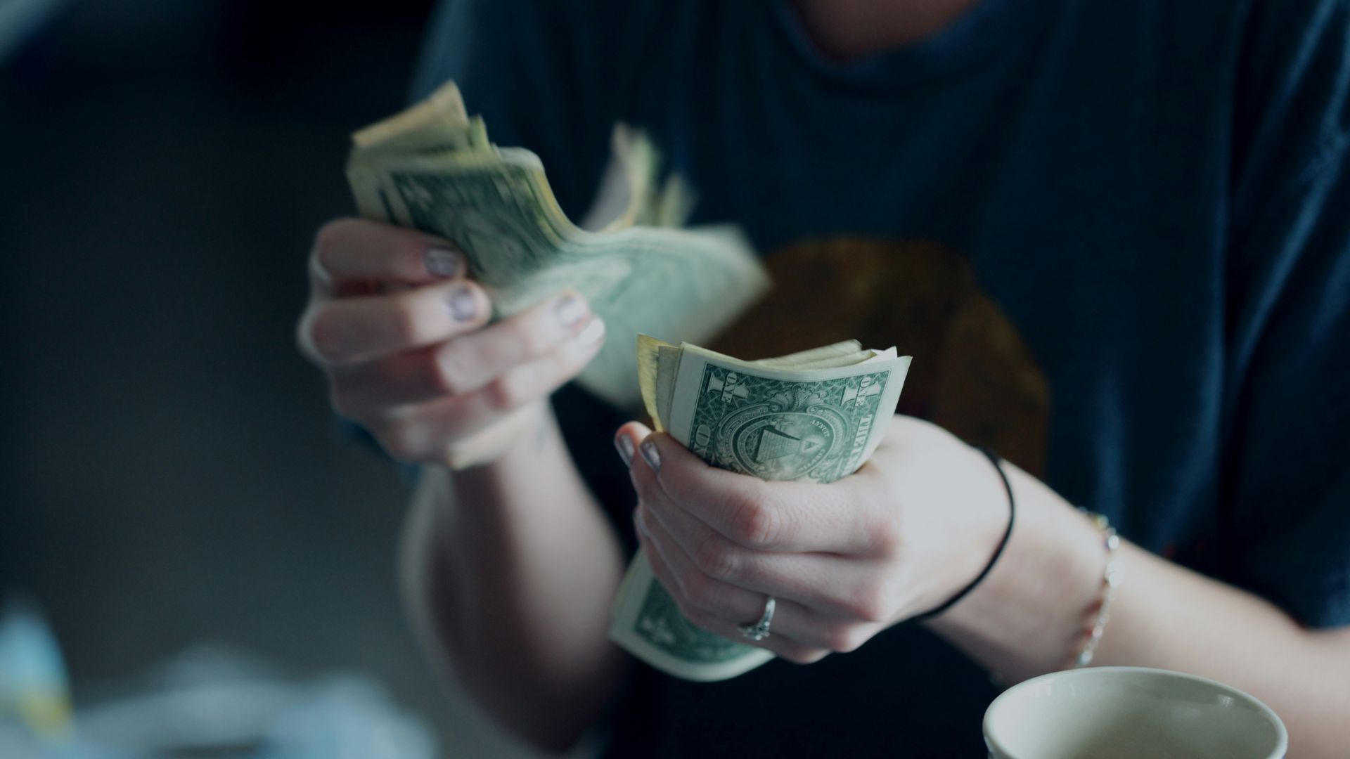 Woman holding a glass jar labeled savings with cash inside