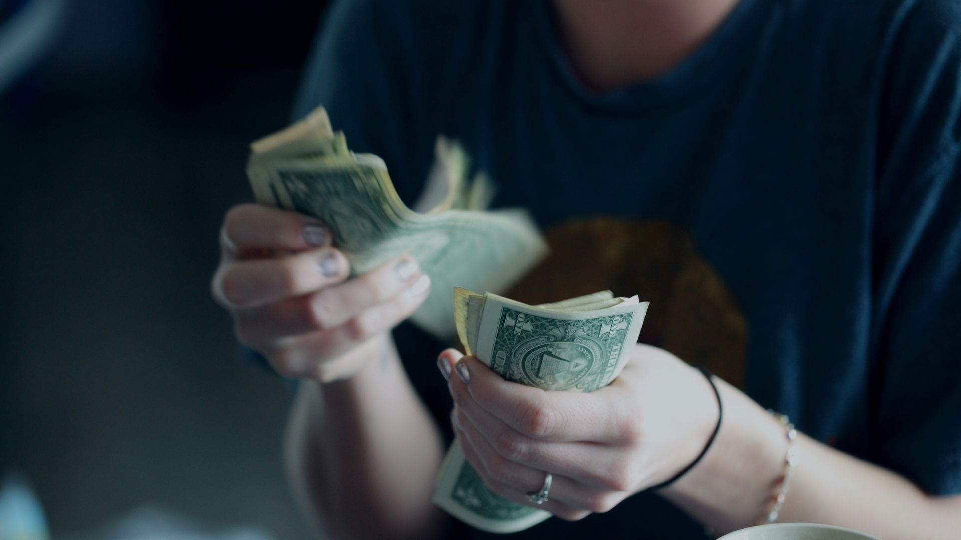 Person counting dollar bills on a flat surface