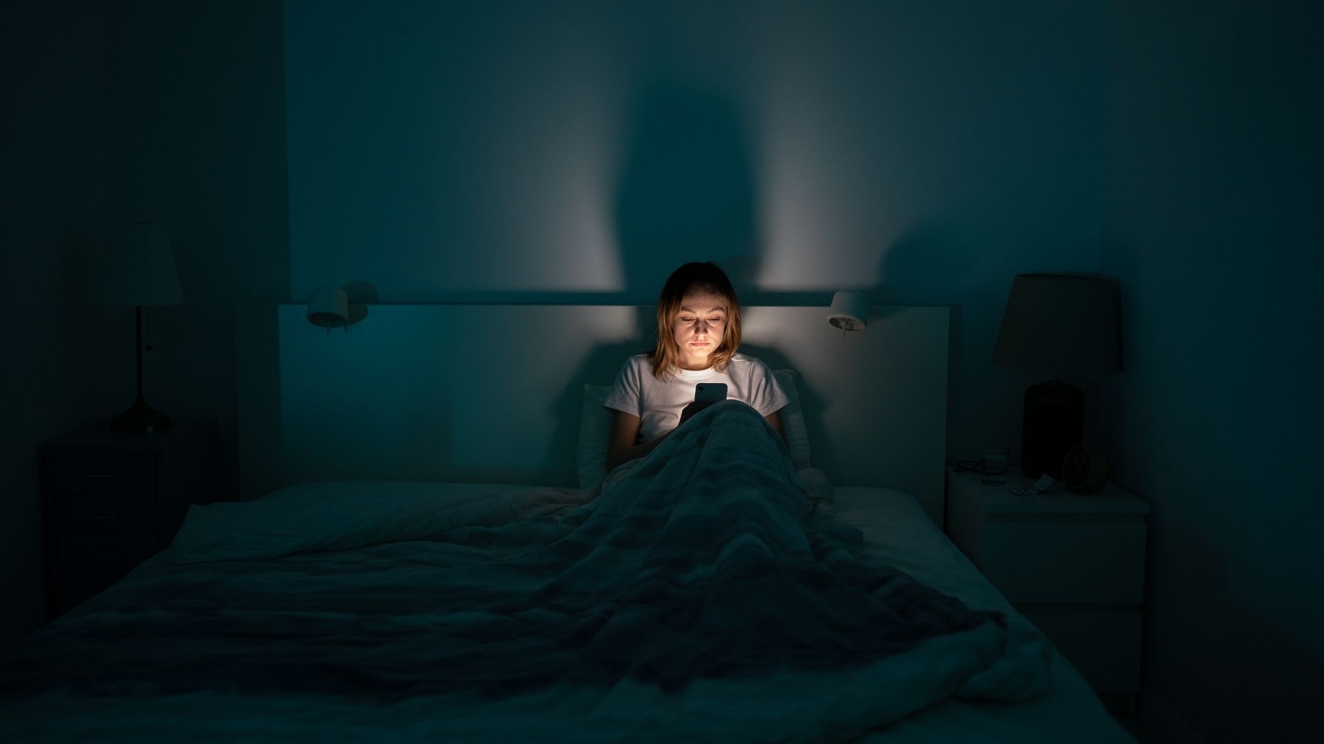 Woman on phone in bed in dark room