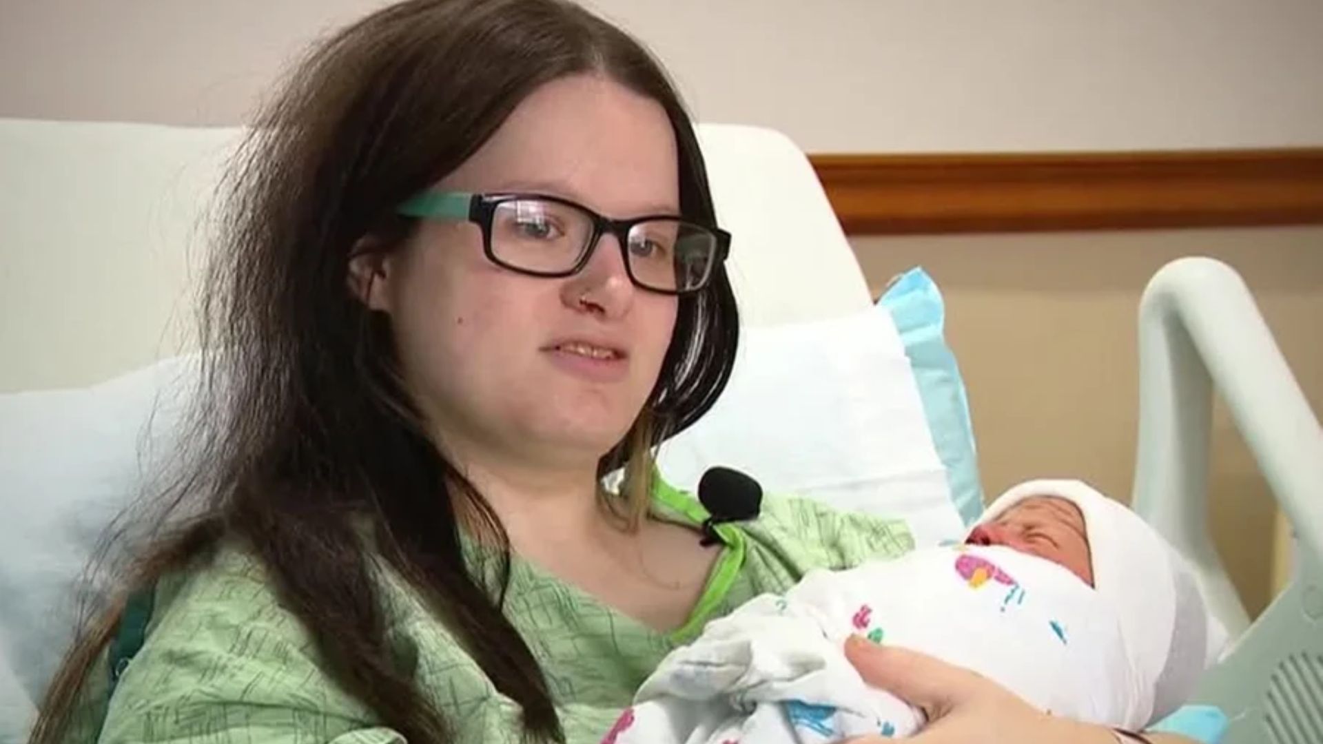 Amethyst Blumberg sits in a hospital bed holding a newborn wrapped in a white blanket.