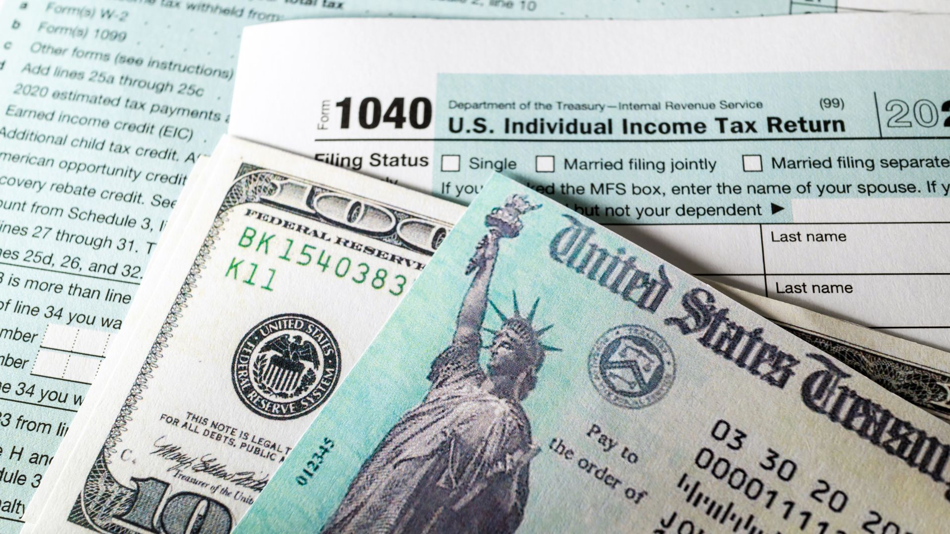 U.S. Treasury tax refund check placed on top of IRS Form 1040 with dollar bills