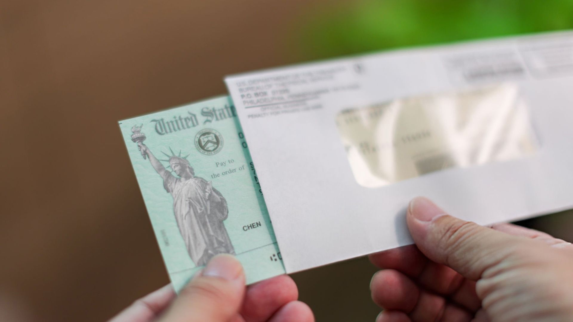 Man holding U.S. government tax refund check with Treasury seal visible