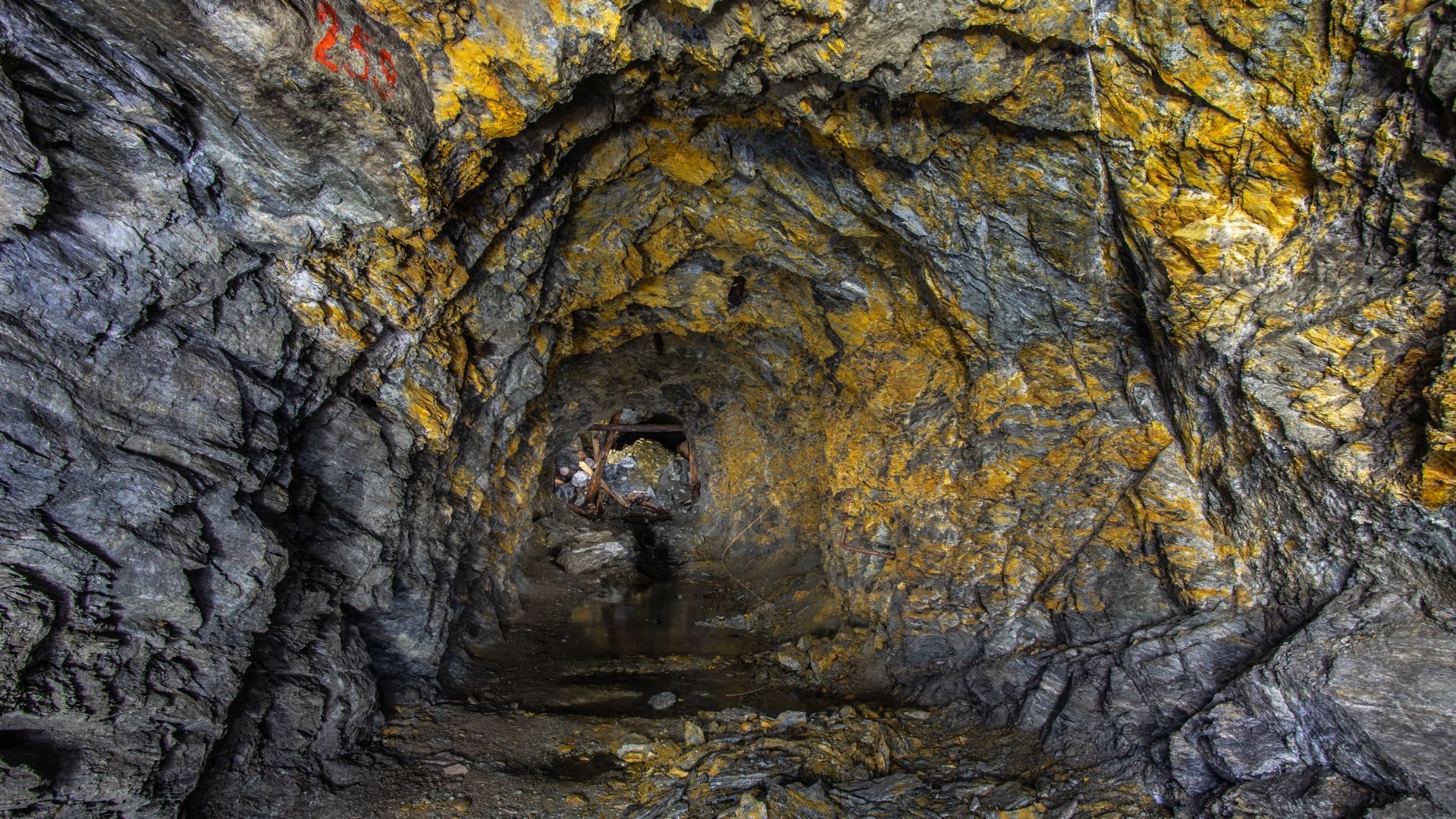 Dimly lit tunnel inside an old gold mine extending deep underground