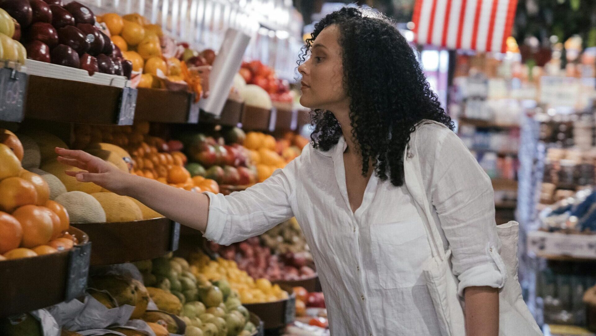 Woman choosing vegetables and fruits inside a market.