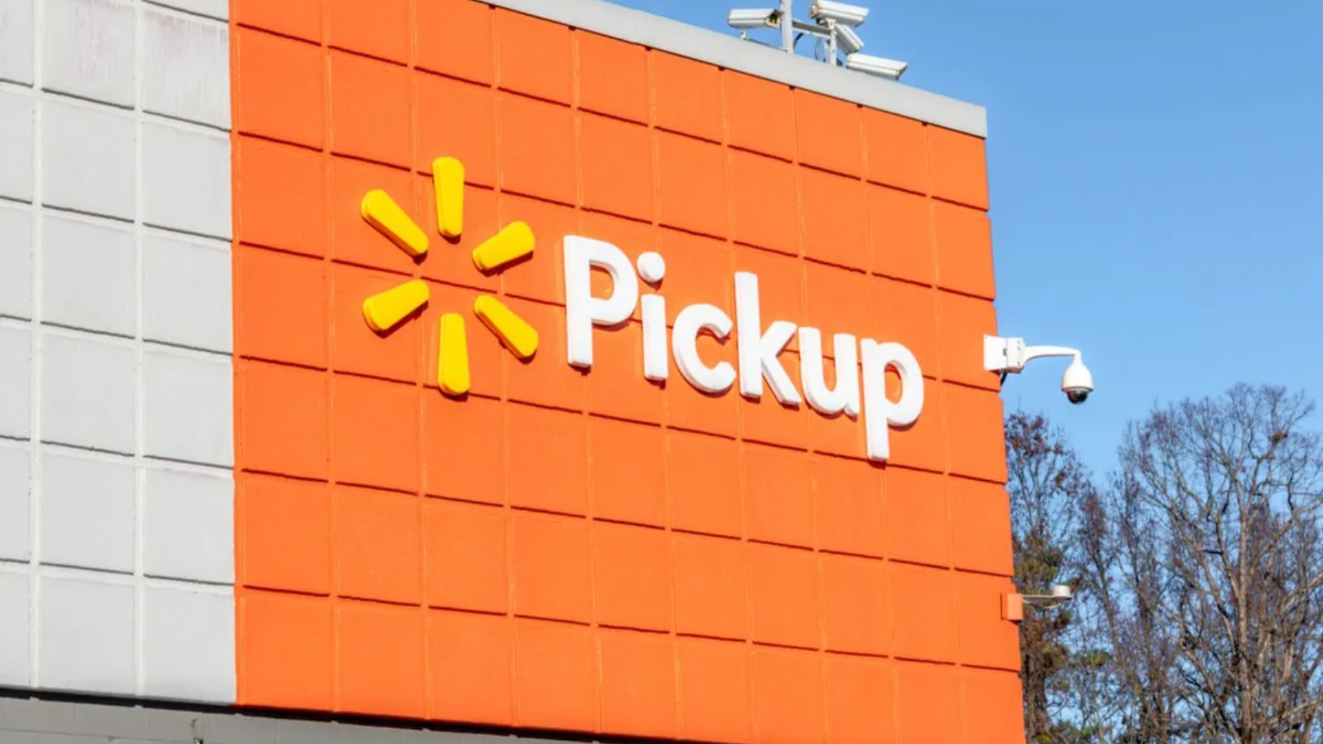 Walmart Pickup sign on an orange exterior wall with security cameras above.