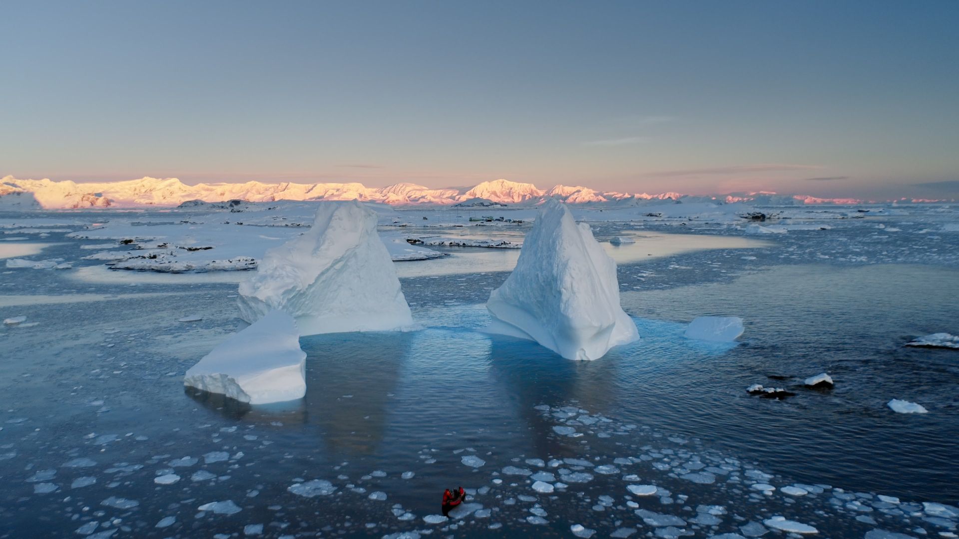 Melting Antarctic glacier meeting blue ocean water under cloudy sky