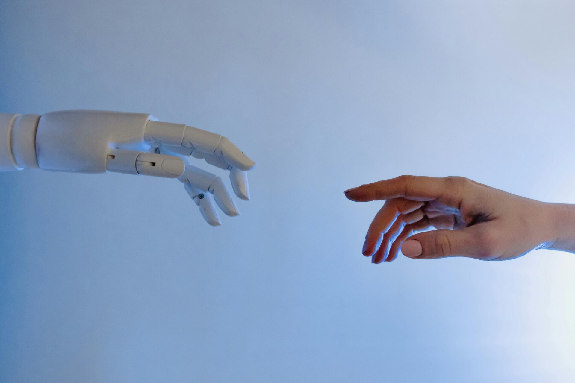 Person reaching toward a humanoid robot hand symbolizing human and artificial intelligence interaction.