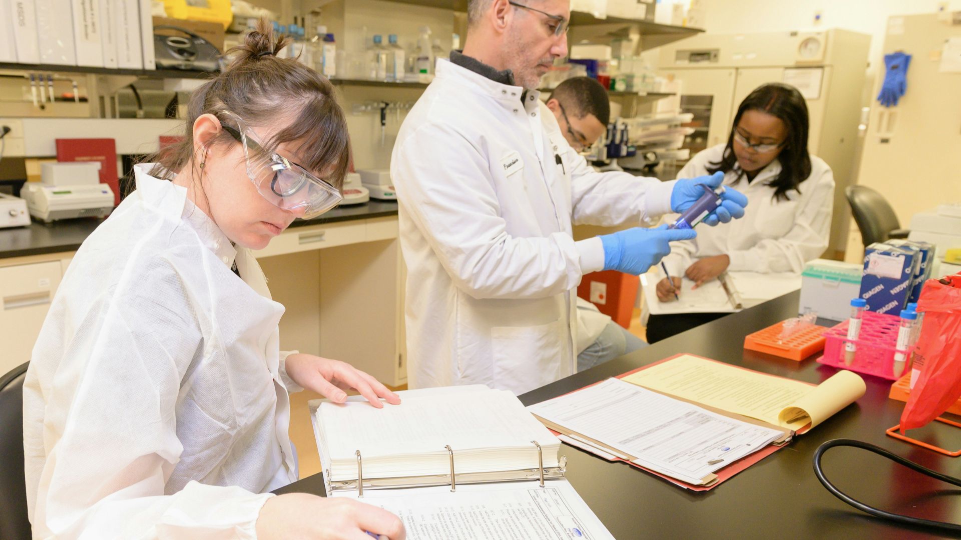Scientists in lab coats working with equipment inside a laboratory