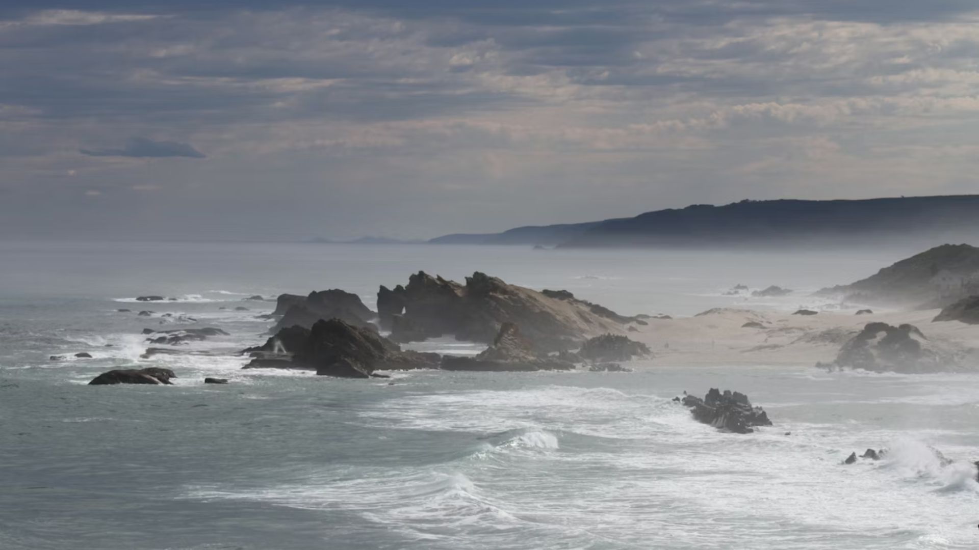 Rocky coastline surrounded by ocean water and mist