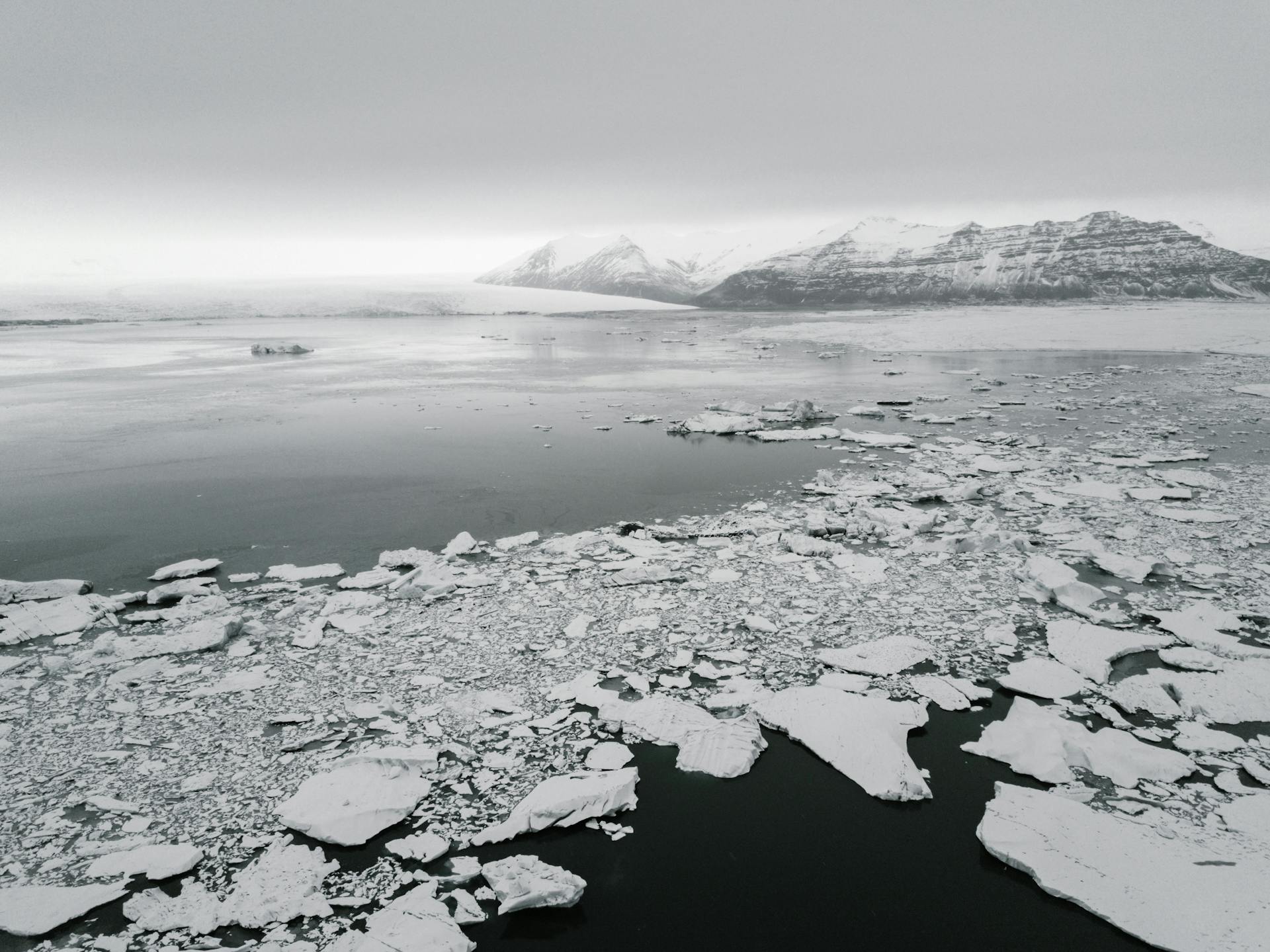 Antarctic landscape with broken ice on water and frozen mounts