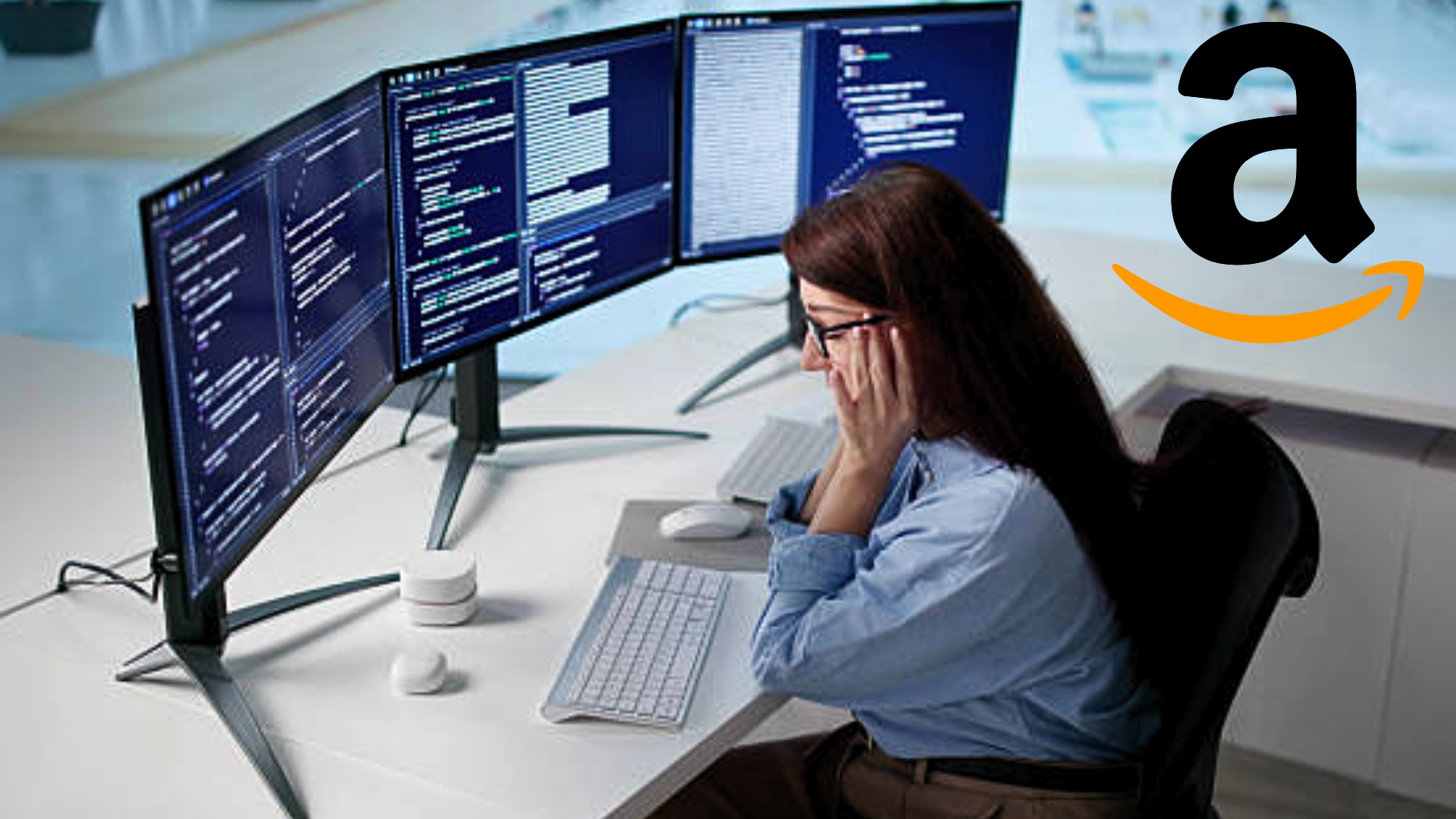 A stressed software engineer sitting at a desk with three monitors showing lines of code, with the Amazon logo in the corner.