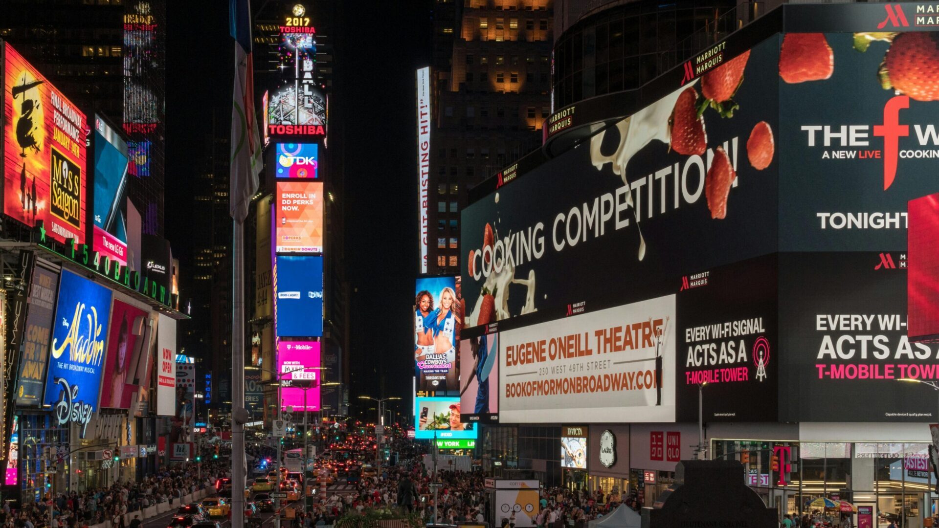 Crowded Times Square intersection with bright billboards and traffic in New York City.