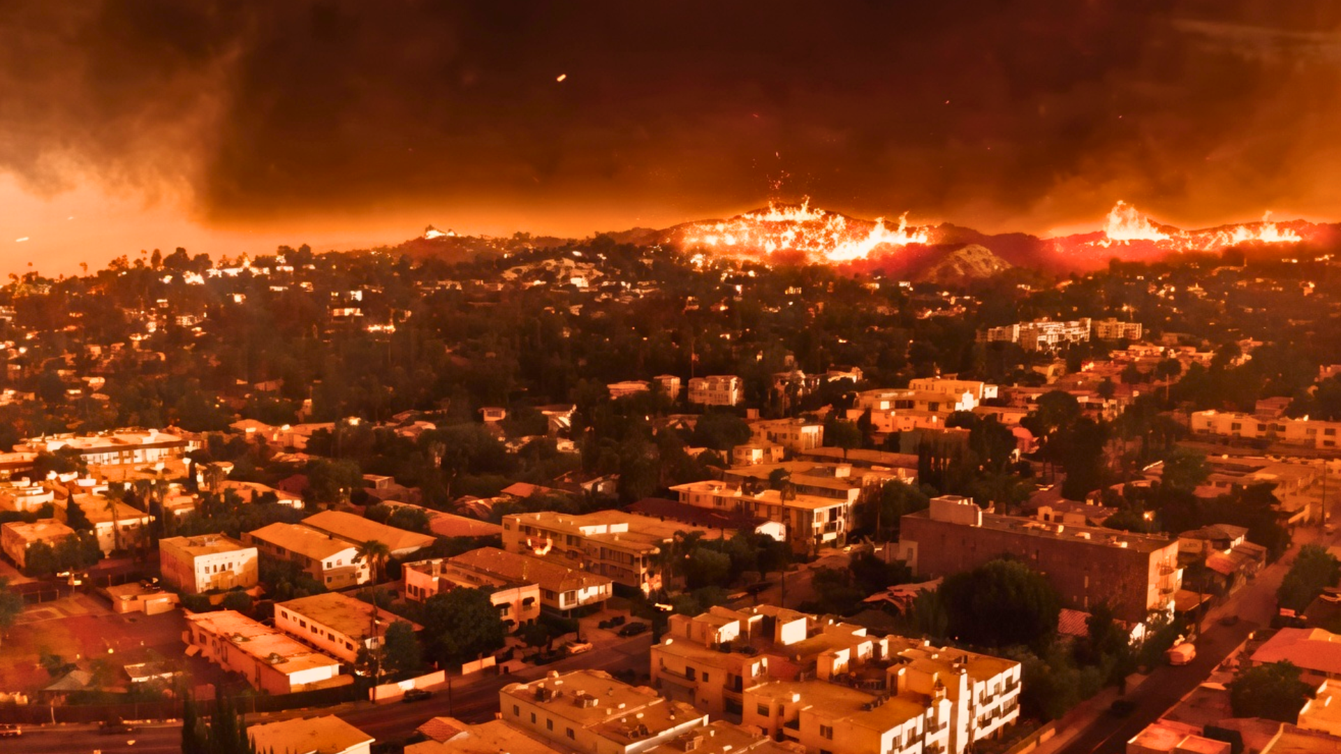 Wildfire burning across hillside neighborhoods with flames and heavy smoke filling the sky.