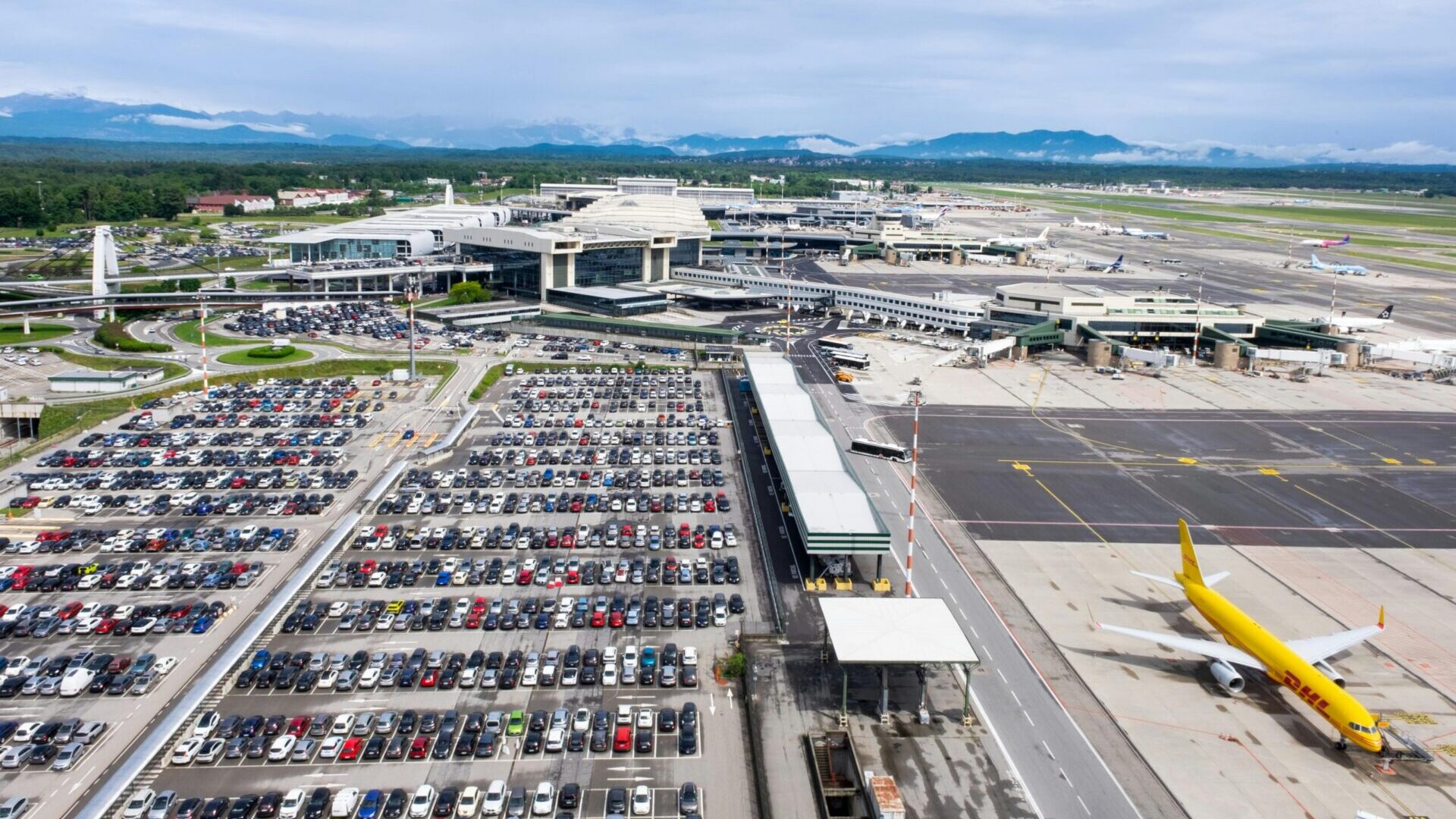 Aerial view of a large airport parking lot filled with rows of parked cars.