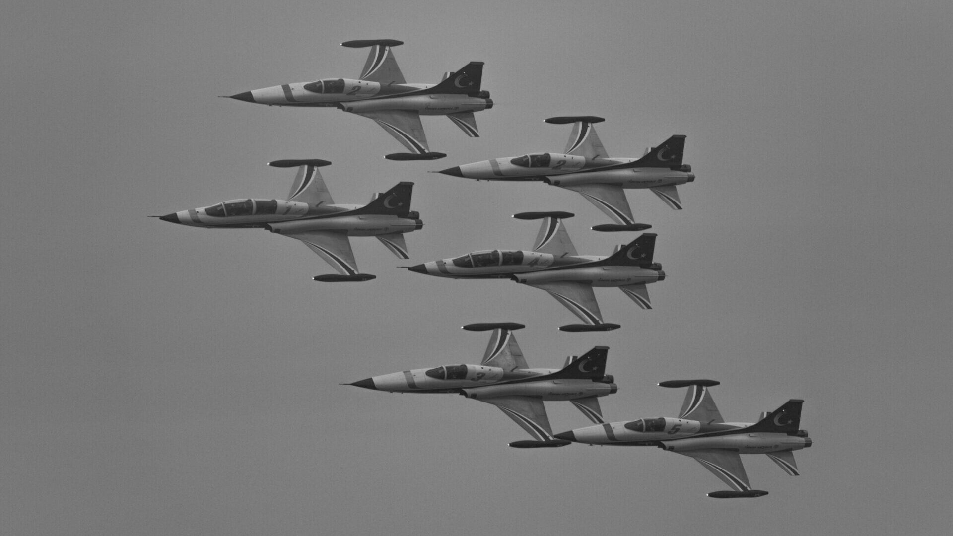 Formation of military jets flying in the sky in tight formation.