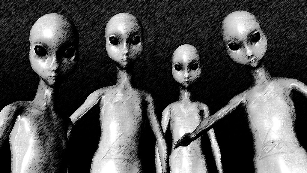 POV of four gray aliens with large black eyes leaning toward the viewer during an alien abduction scene.