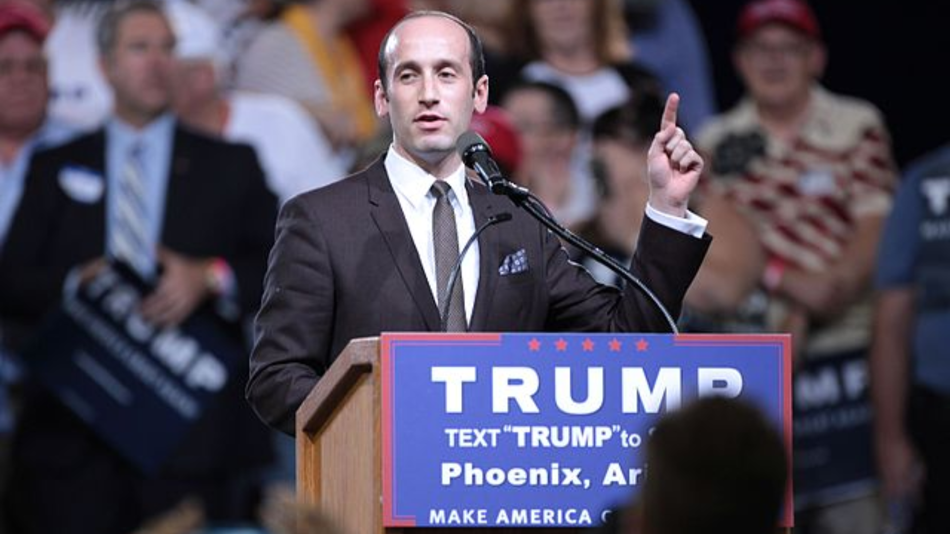 Stephen Miller speaking at a podium in Phoenix, Arizona.