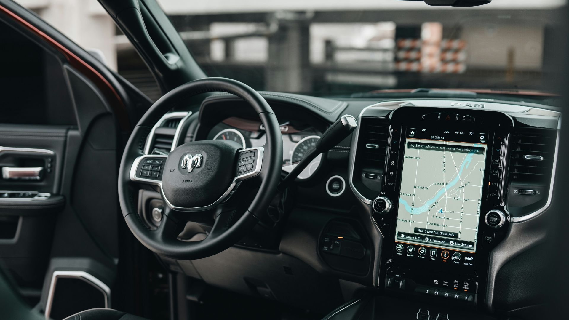 Modern vehicle dashboard with steering wheel and large navigation screen active.
