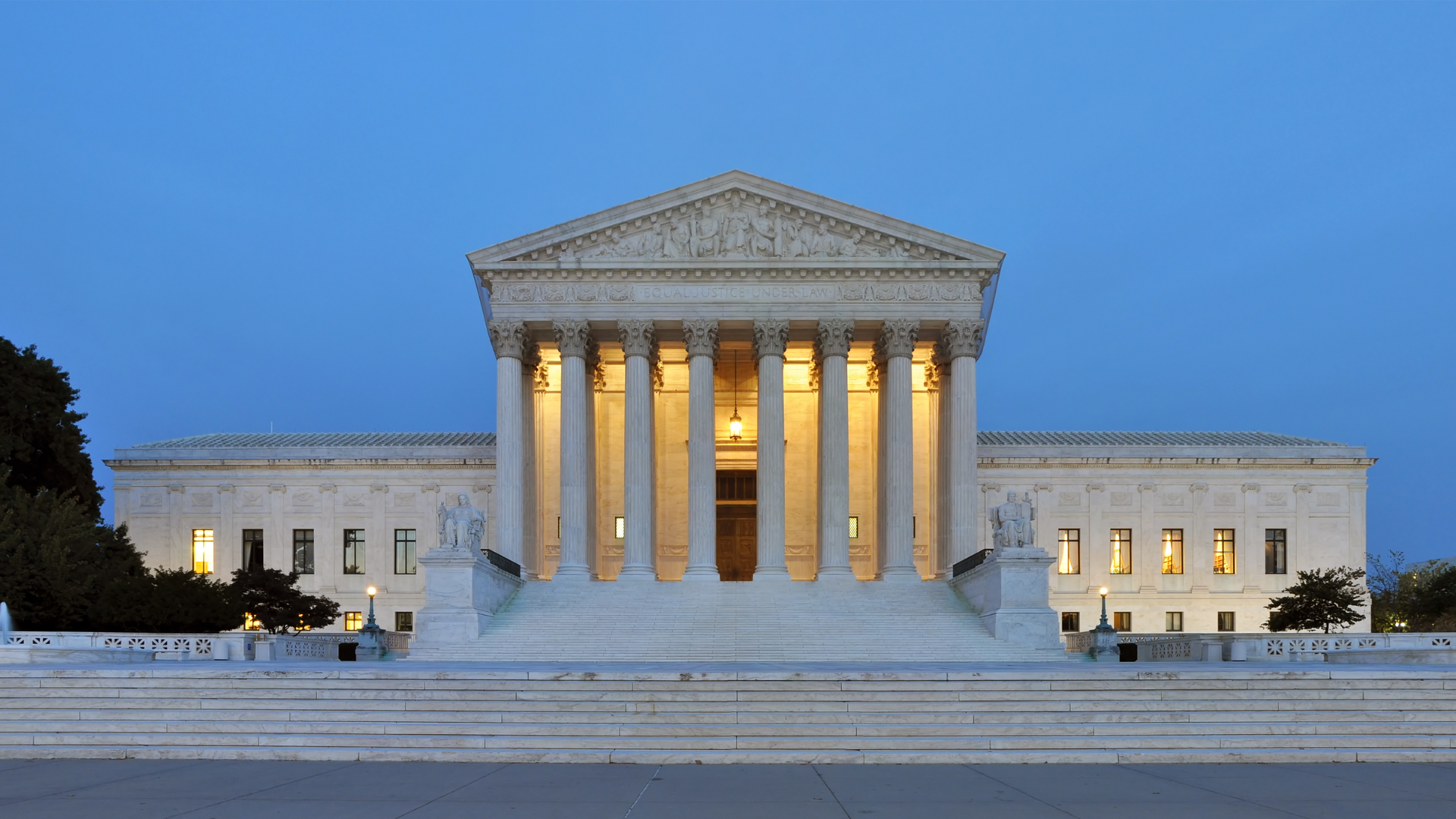 U.S. Supreme Court building illuminated at dusk with columns.