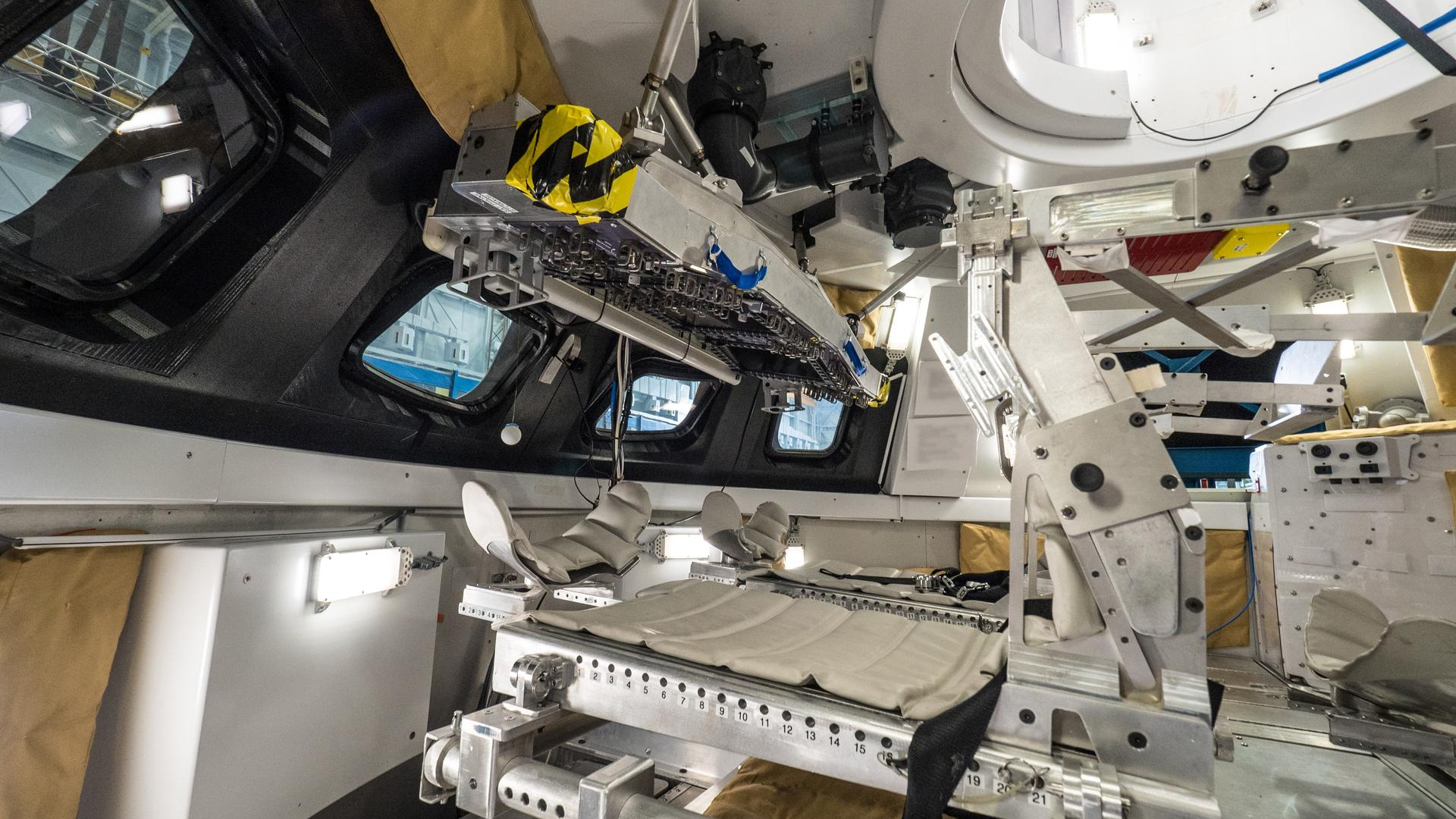 Interior view of the Orion spacecraft crew module, showing specialized reclining seats and technical equipment designed for deep space missions.