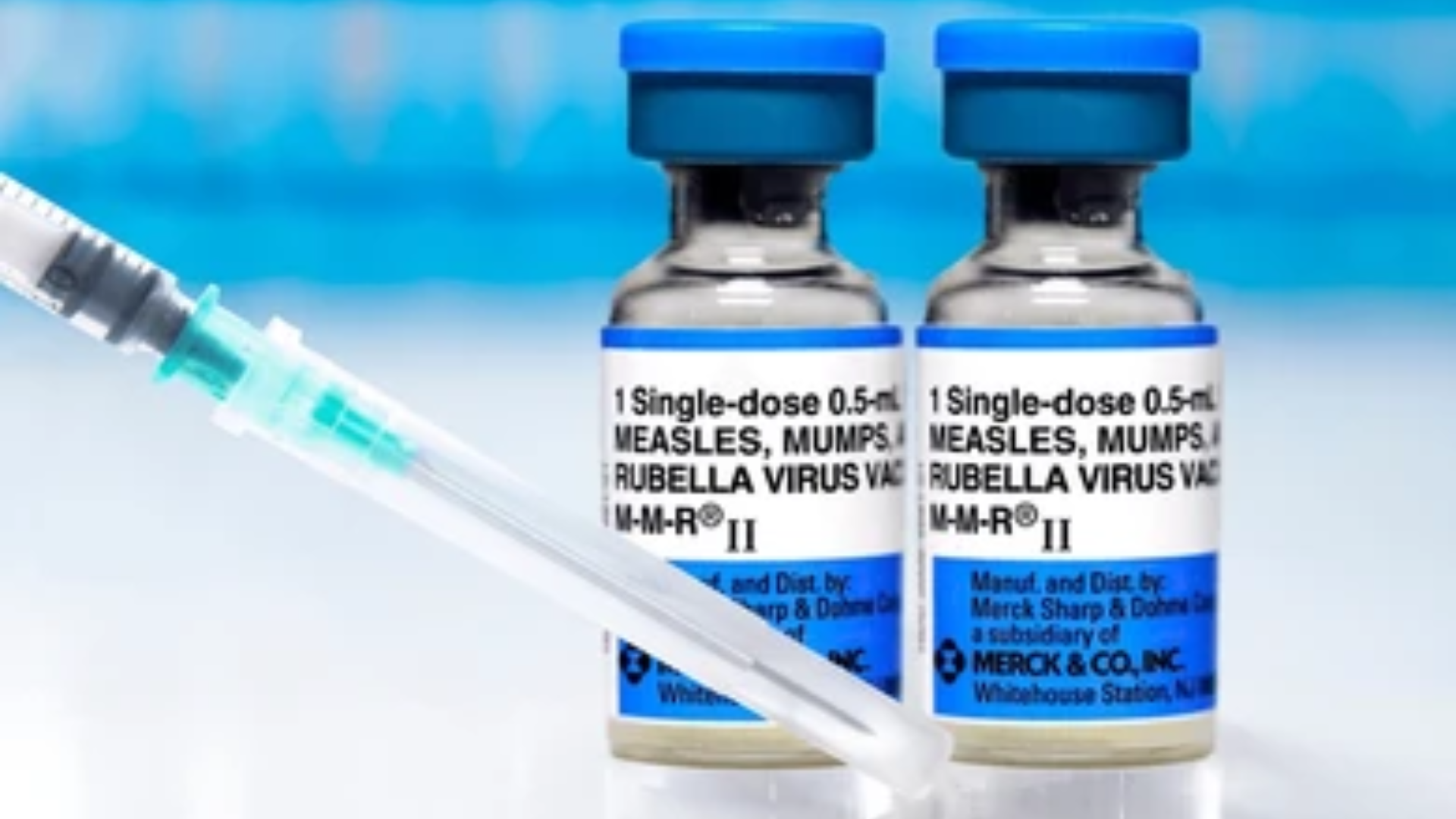 MMR vaccine vials and syringe on a clinical surface.
