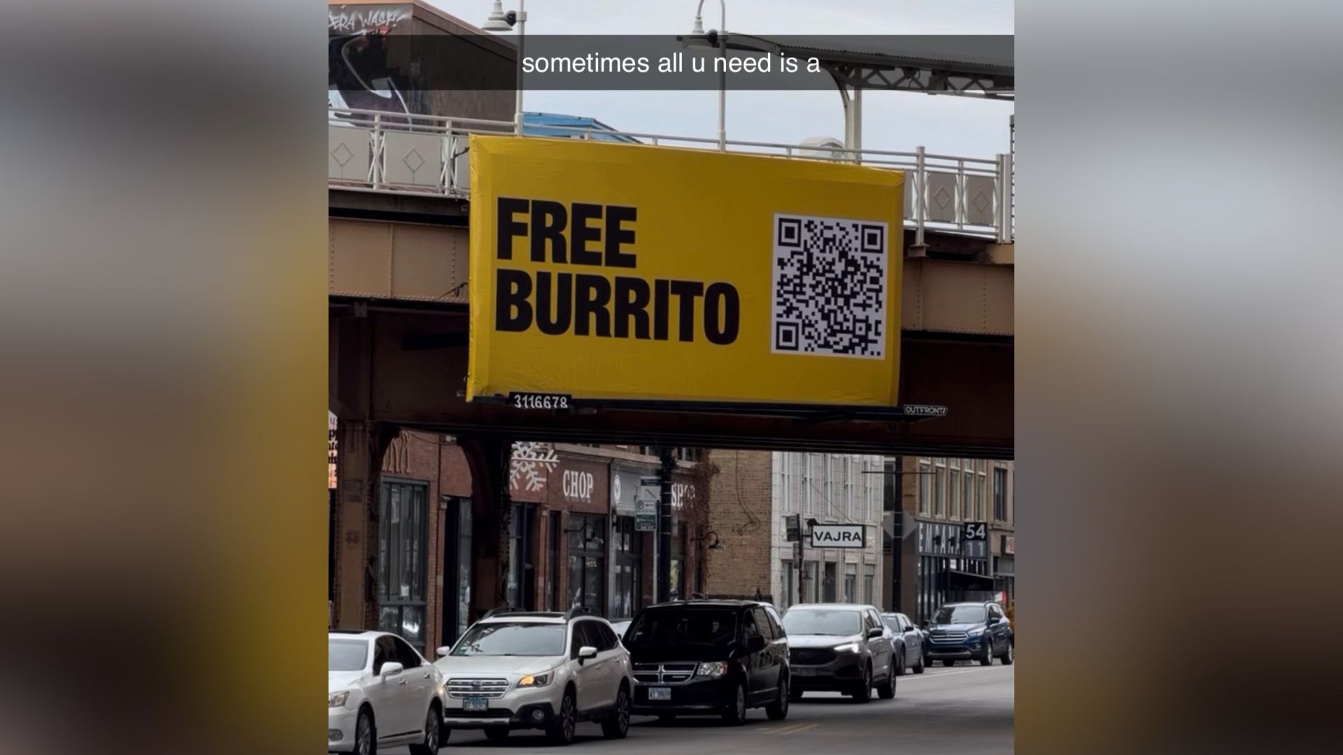 Street billboard offering free burrito with QR code above busy urban road.