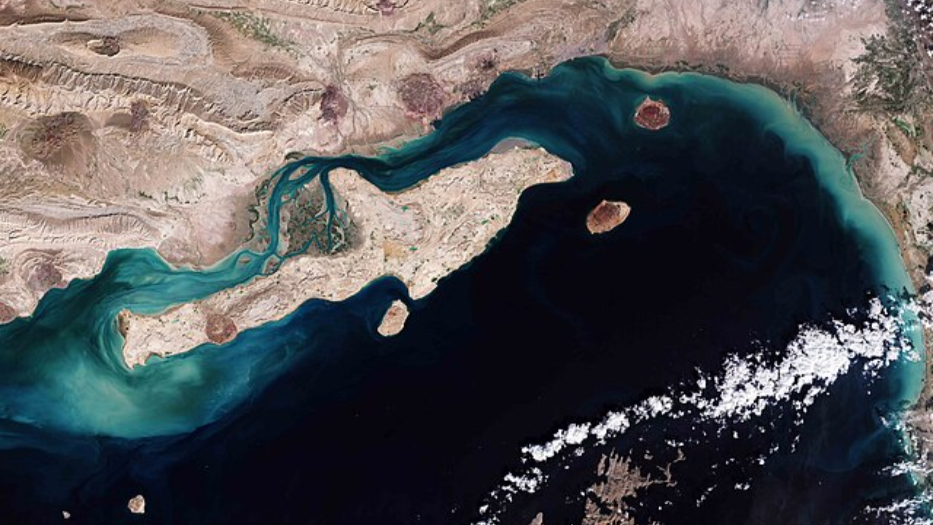 A satellite view showing the narrow waterway between the mountainous coastlines of Iran and the Arabian Peninsula.
