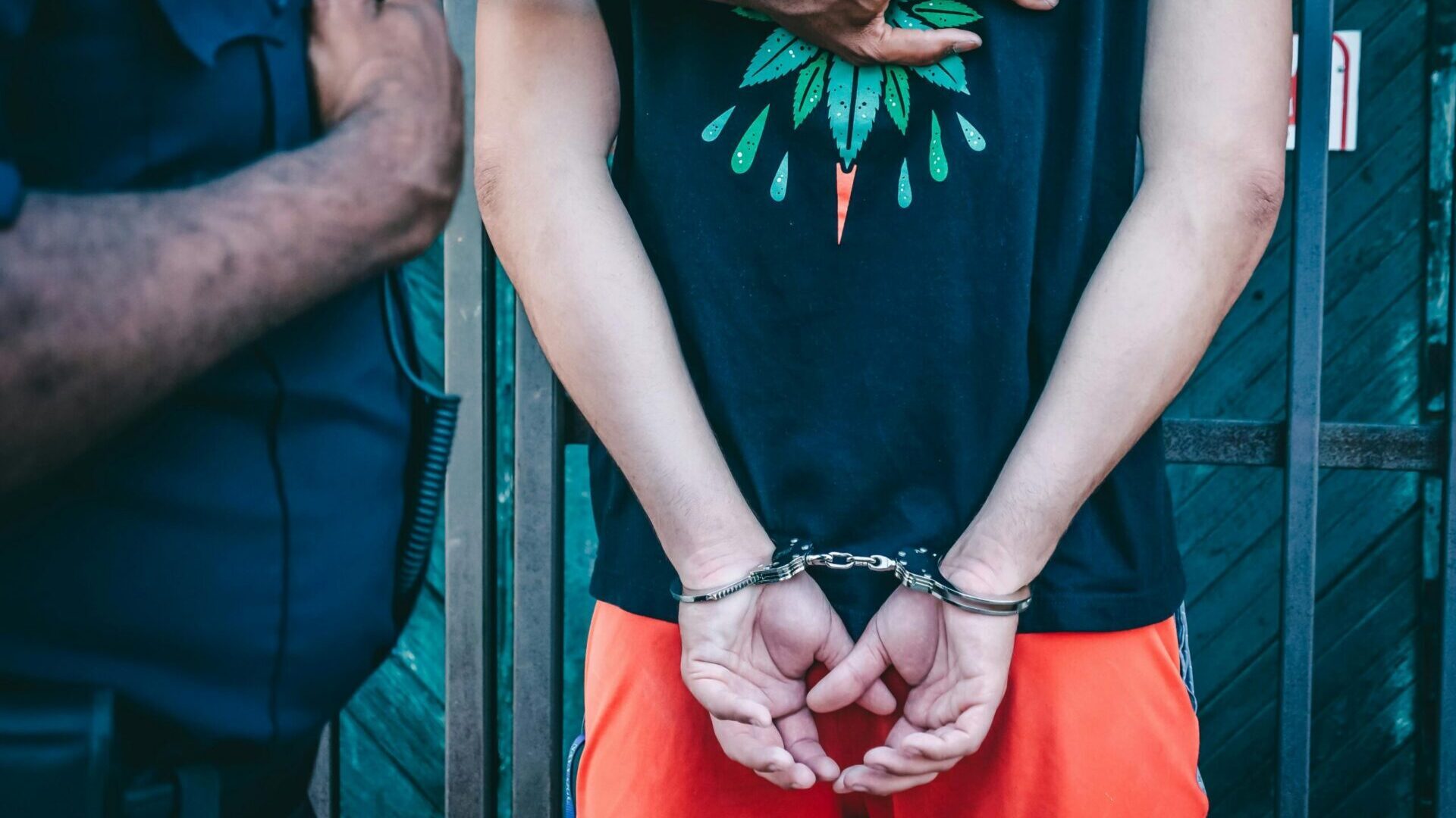 Person in a black shirt being handcuffed by a police officer.