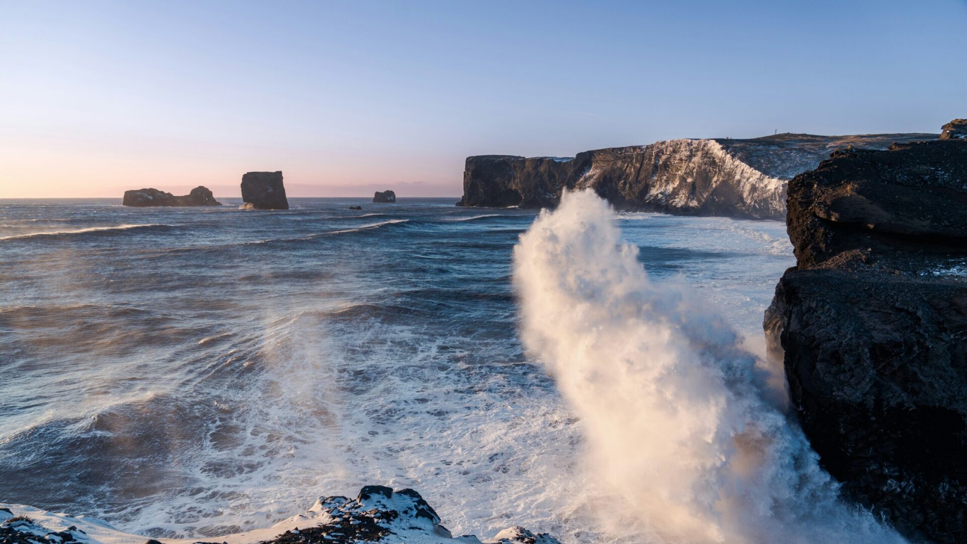 Powerful ocean waves crashing against rocks along the coastline during hazardous surf conditions