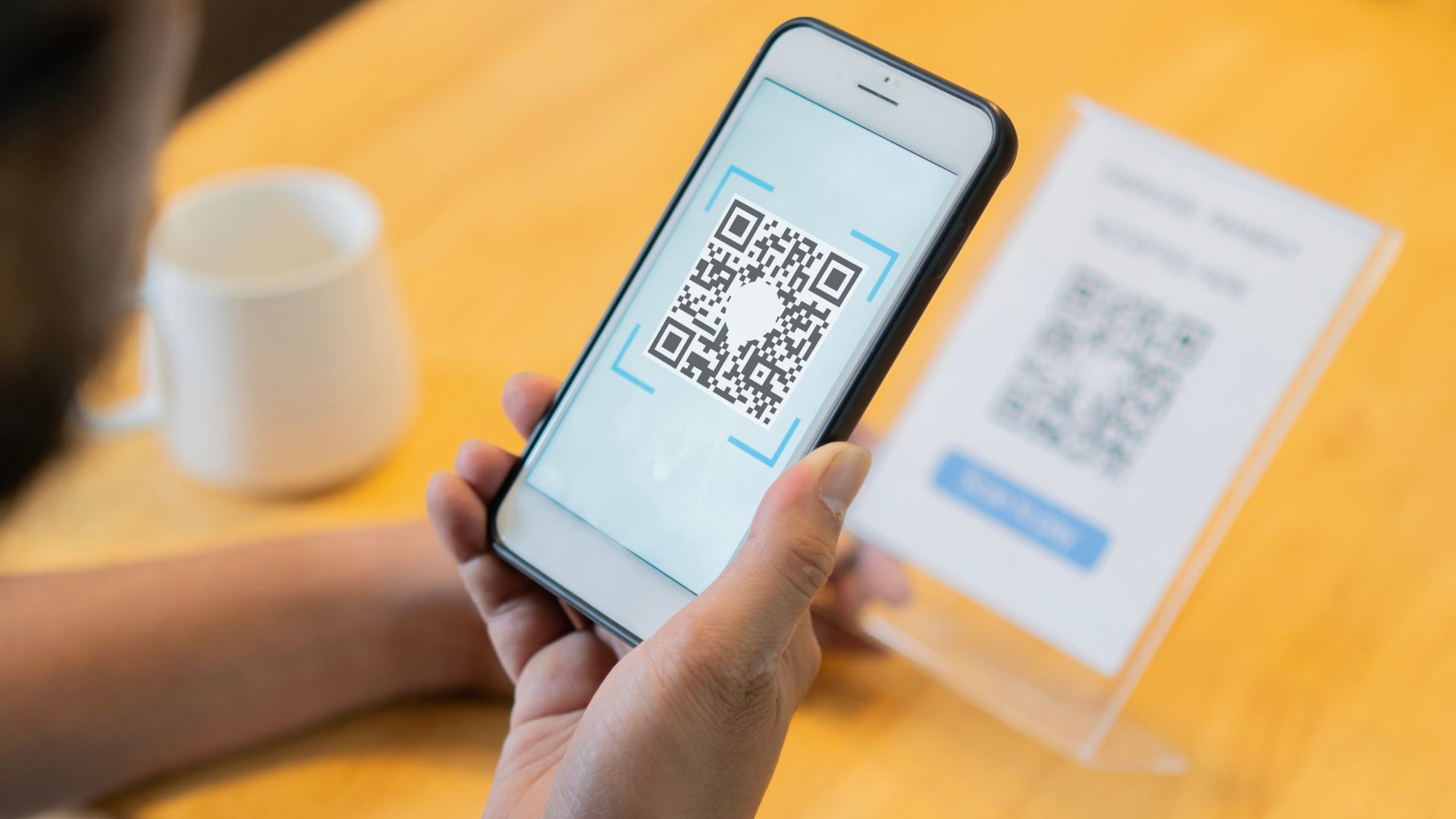 Person holding smartphone scanning QR code on screen for promotion.